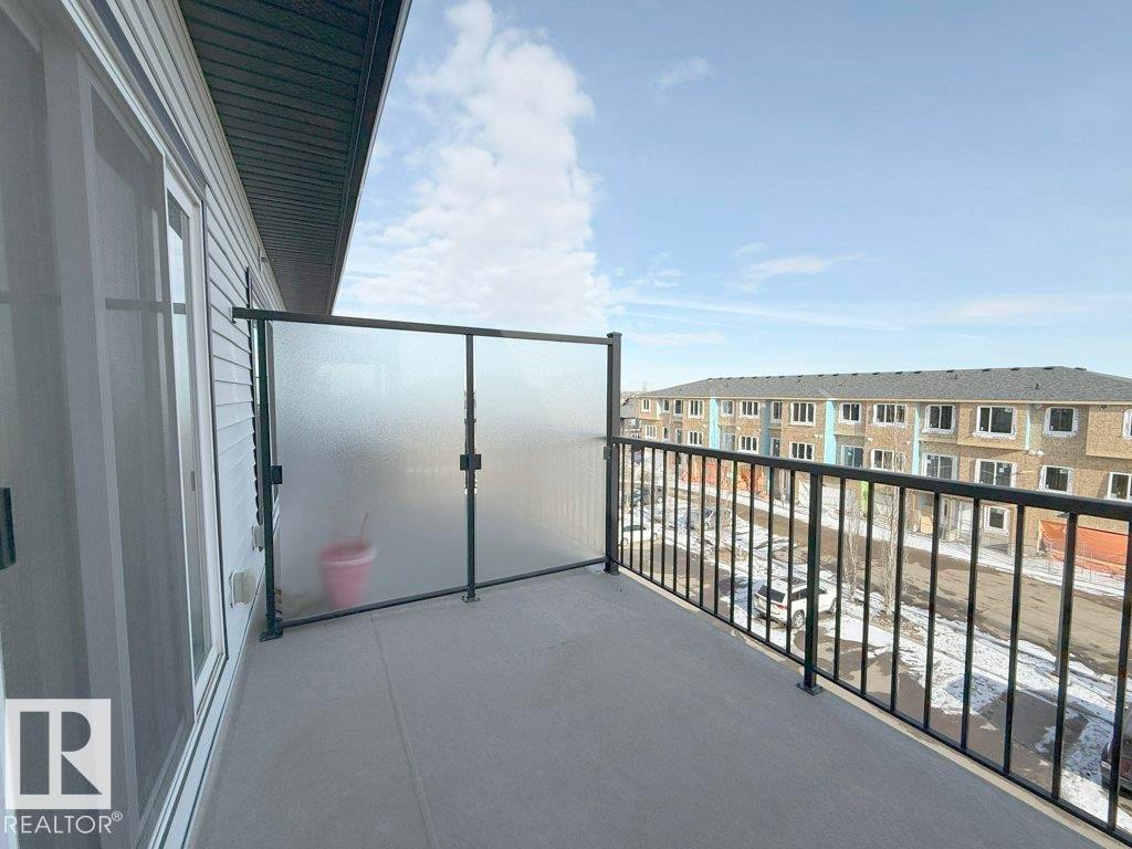 The property features a private balcony with a concrete floor, a black metal railing, and frosted glass privacy panels - 429 390 Windermere Rd, Edmonton, AB - Outdoor With Balcony With Exterior