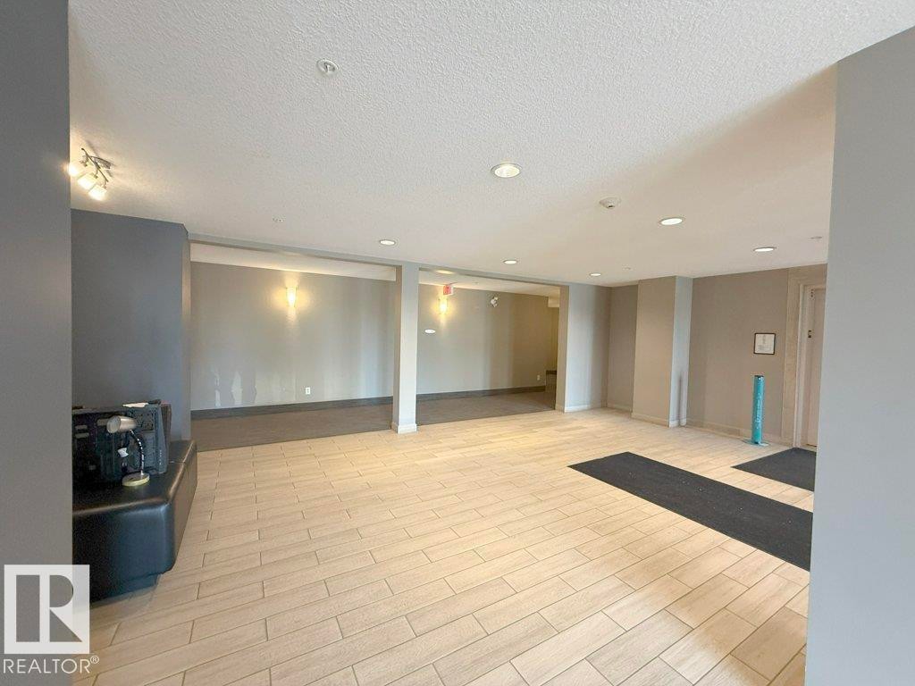 Spacious interior room featuring light-colored flooring, recessed lighting, and wall sconces providing illumination - 429 390 Windermere Rd, Edmonton, AB - Indoor Photo Showing Other Room