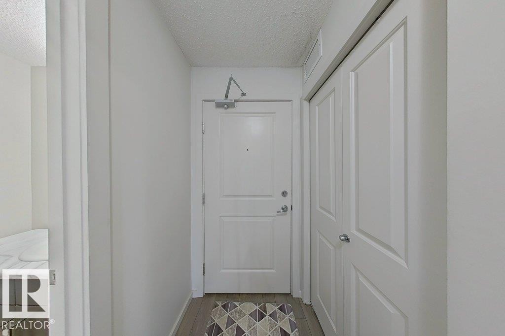 The property features a front entry with a white paneled door, light wood flooring, and a closet with white paneled bifold doors - 429 390 Windermere Rd, Edmonton, AB - Indoor Photo Showing Other Room