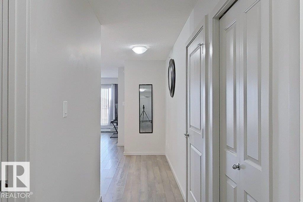 This hallway features light-toned flooring and white walls, creating a bright and open atmosphere - 429 390 Windermere Rd, Edmonton, AB - Indoor Photo Showing Other Room
