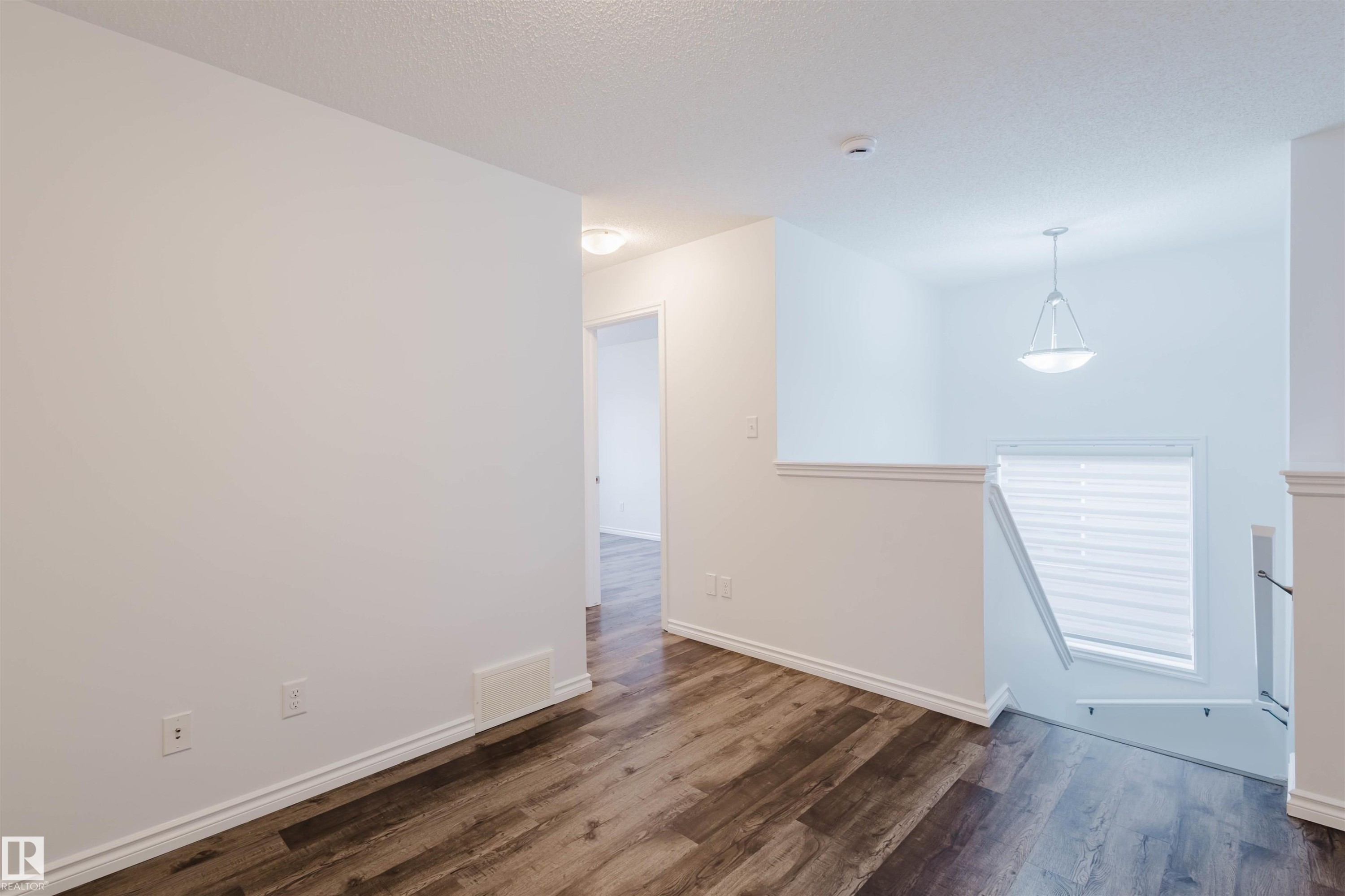 Empty room featuring dark wood-style flooring and a textured ceiling - Edmonton, AB - Indoor Photo Showing Other Room