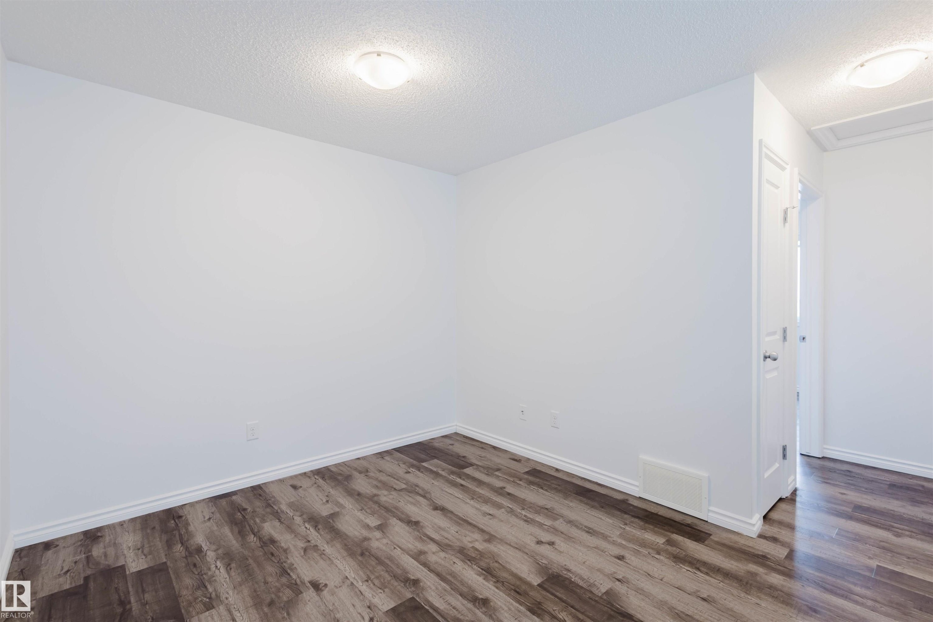 Spare room featuring a textured ceiling and dark wood-style floors - Edmonton, AB - Indoor Photo Showing Other Room