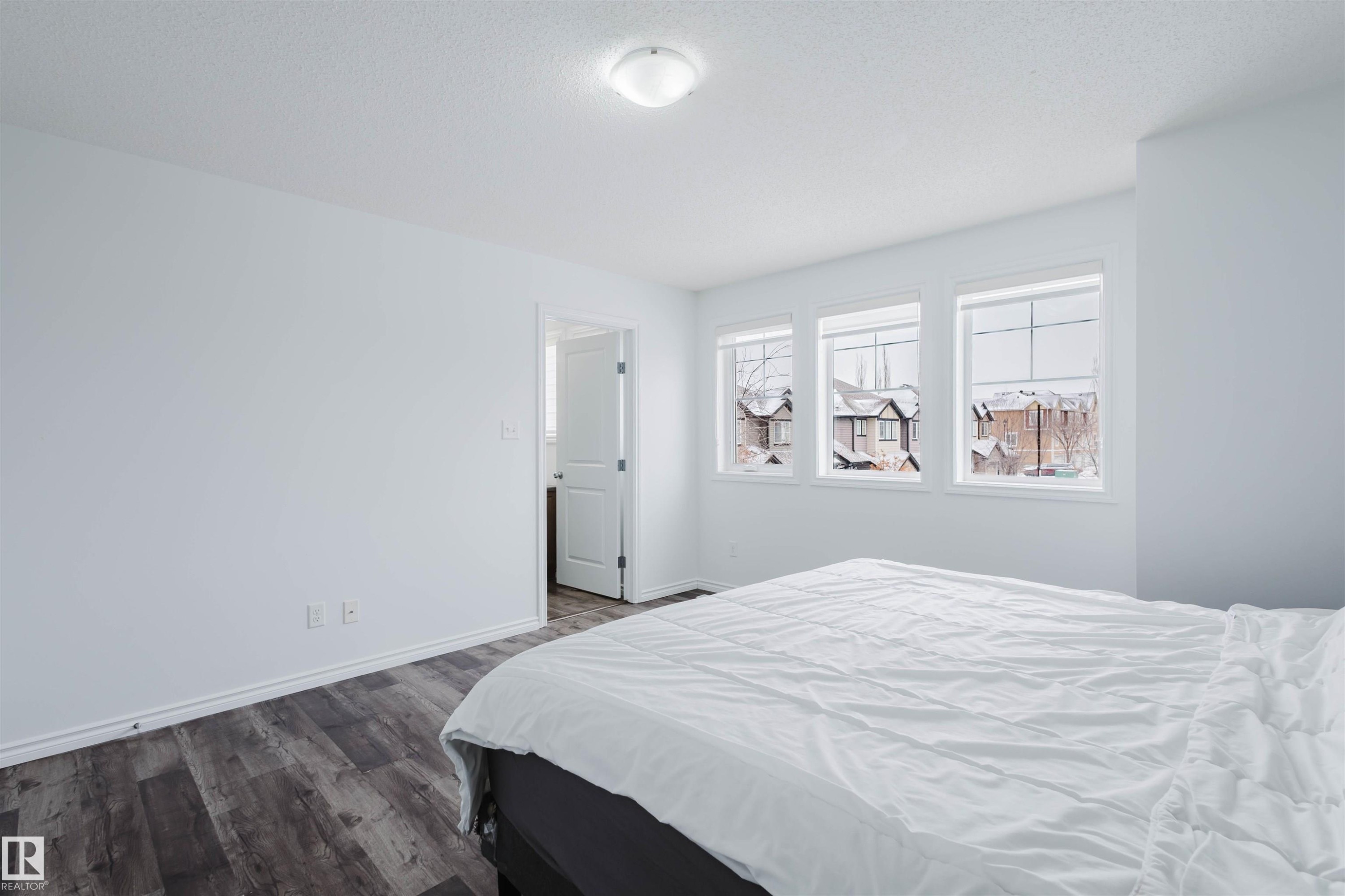 Bedroom with dark wood-type flooring and a textured ceiling - Edmonton, AB - Indoor Photo Showing Bedroom