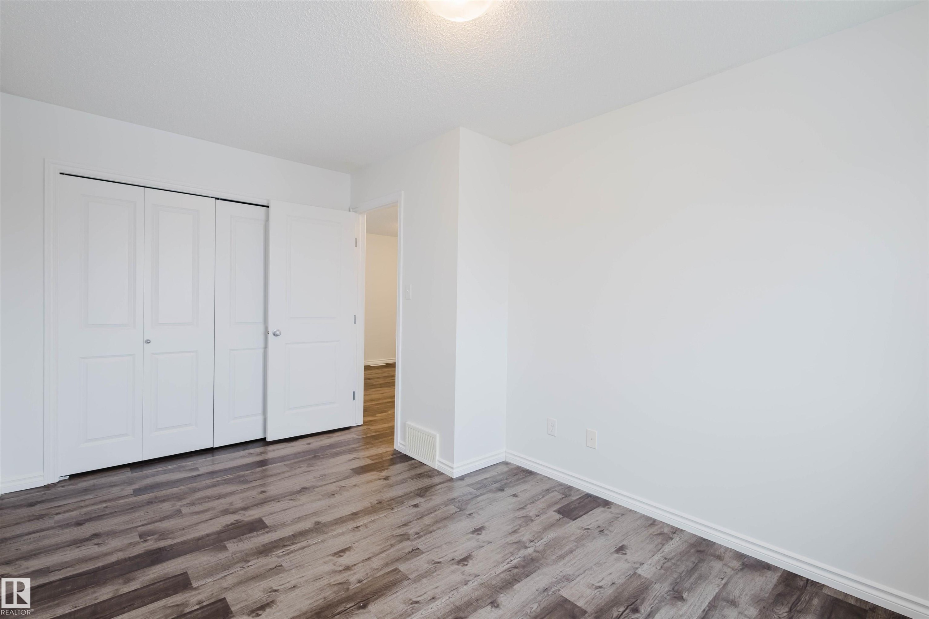 Unfurnished bedroom featuring wood finished floors, a closet, and a textured ceiling - Edmonton, AB - Indoor Photo Showing Other Room