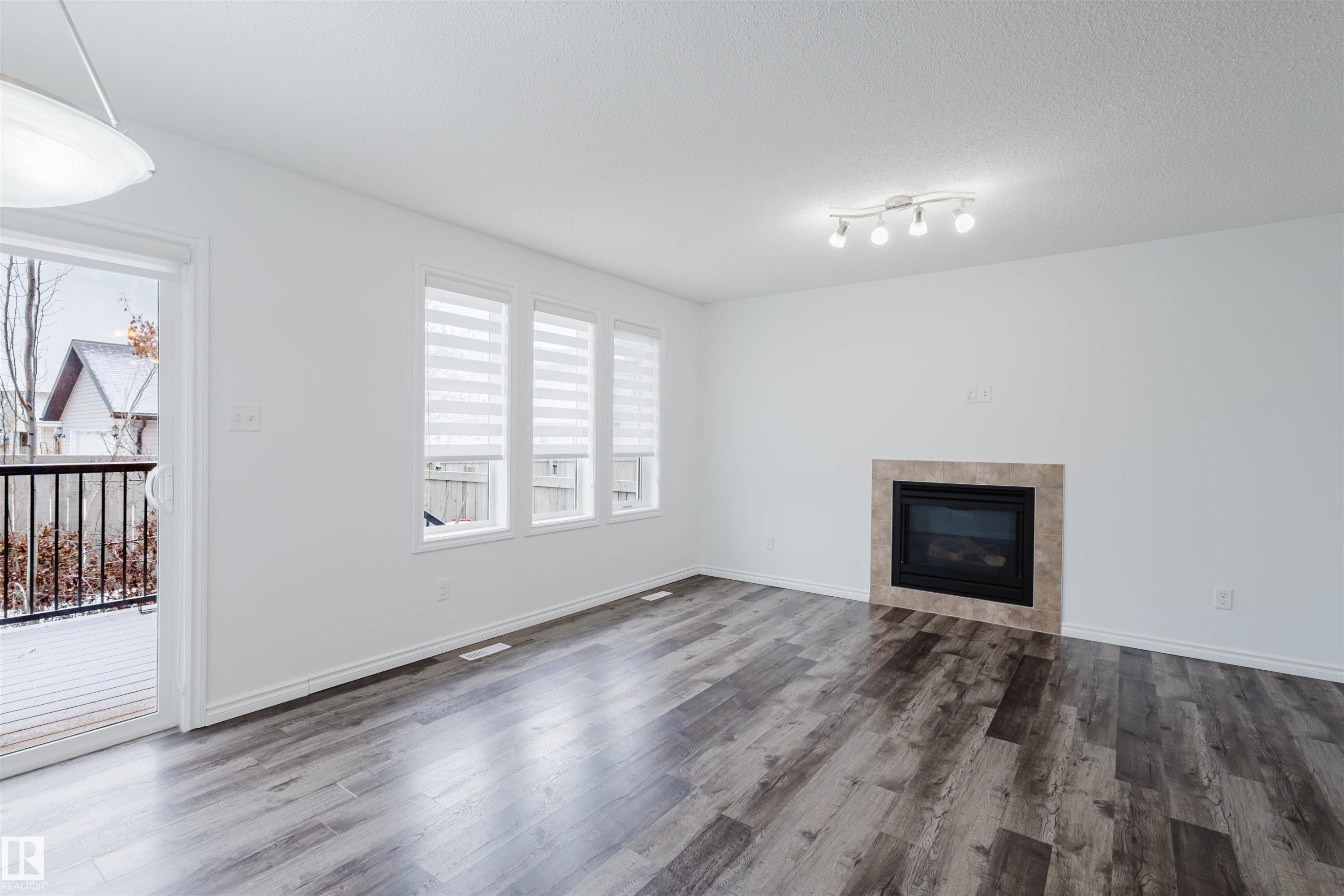 Unfurnished living room featuring a tile fireplace, dark wood-type flooring, and a textured ceiling - Edmonton, AB - Indoor Photo Showing Living Room With Fireplace