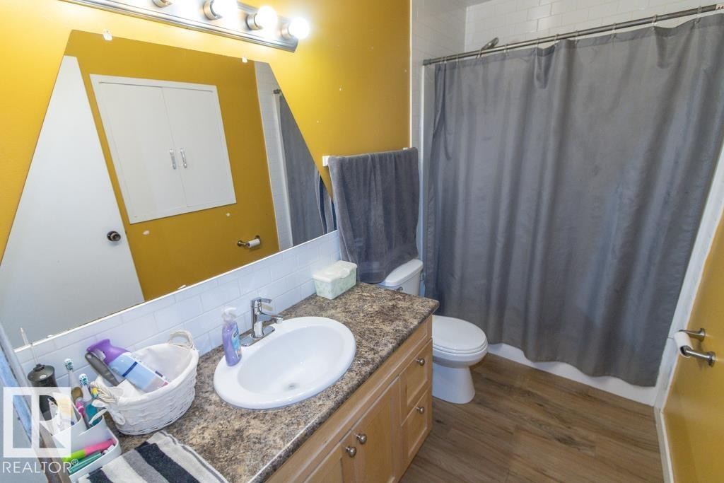 Bathroom featuring a vanity with a countertop and sink, a toilet, and a shower with a shower curtain - 5016 47 St, Myrnam, AB - Indoor Photo Showing Bathroom