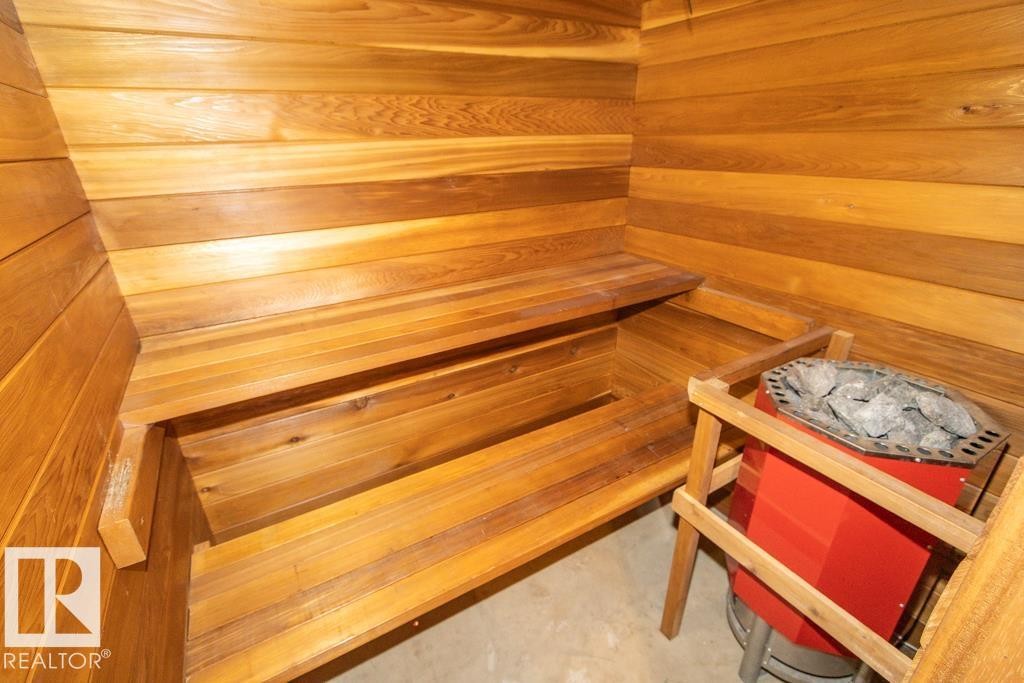 This sauna features wooden walls and benches, with a red heating unit containing rocks - 5016 47 St, Myrnam, AB - Indoor Photo Showing Other Room