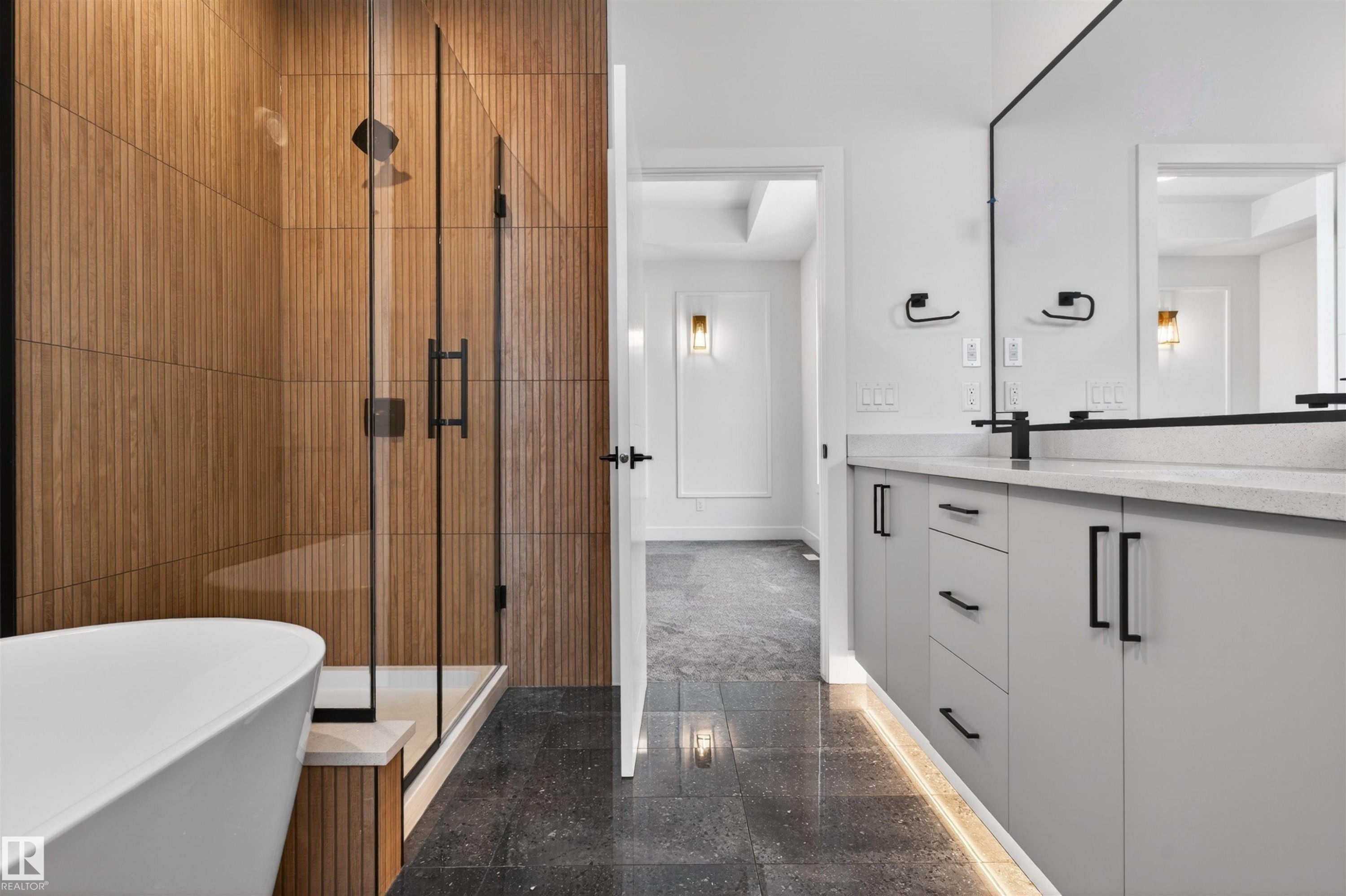 Contemporary bathroom featuring a freestanding tub, a glass-enclosed shower with wood-paneled walls, a double vanity with a light-colored countertop, and dark-toned floor tiles - 11 Redbud Way, St. Albert, AB - Indoor Photo Showing Bathroom