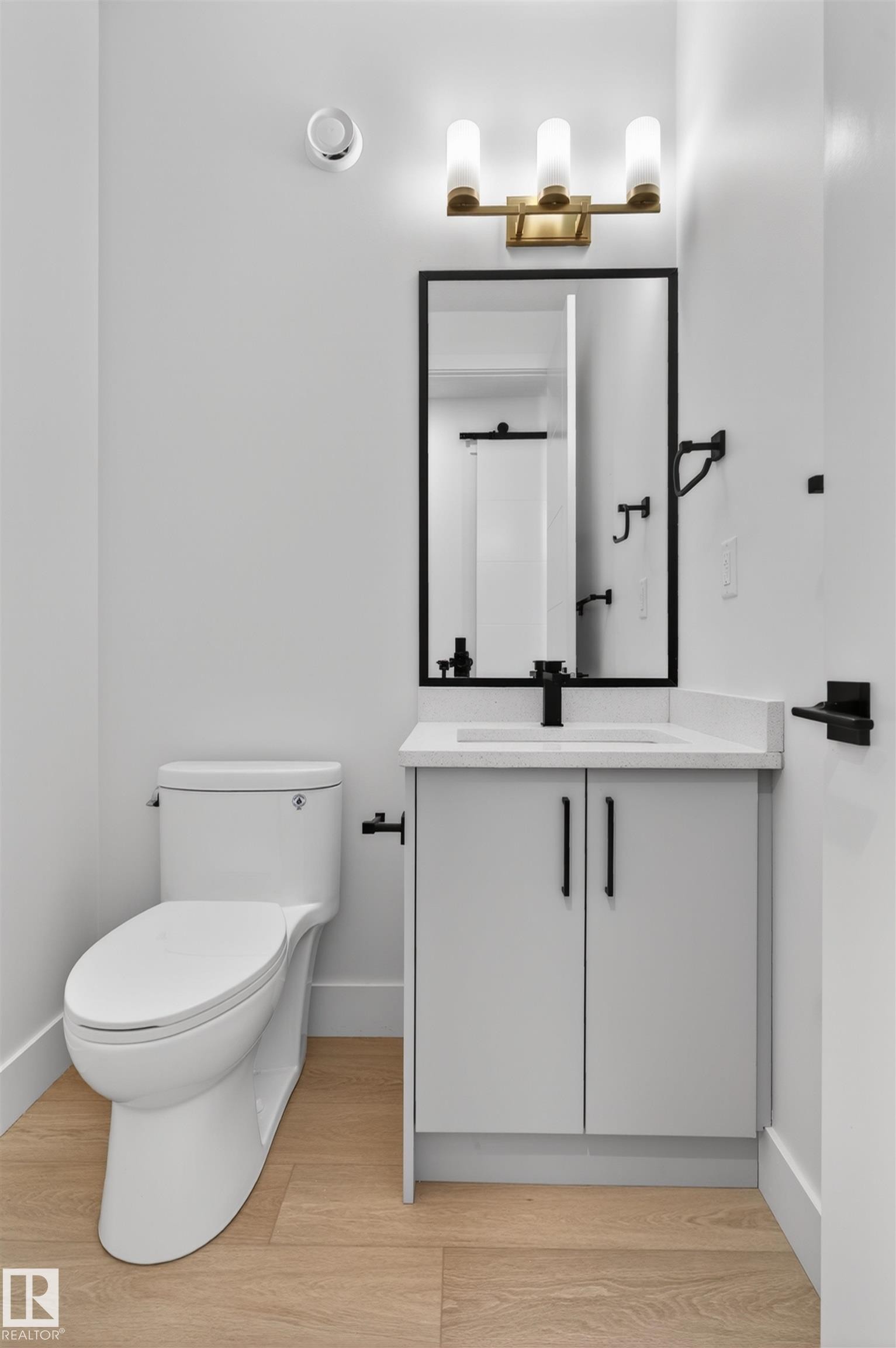 The bathroom features a modern vanity with a white countertop and a rectangular sink, complemented by a black-framed mirror and a three-light fixture - 11 Redbud Way, St. Albert, AB - Indoor Photo Showing Bathroom