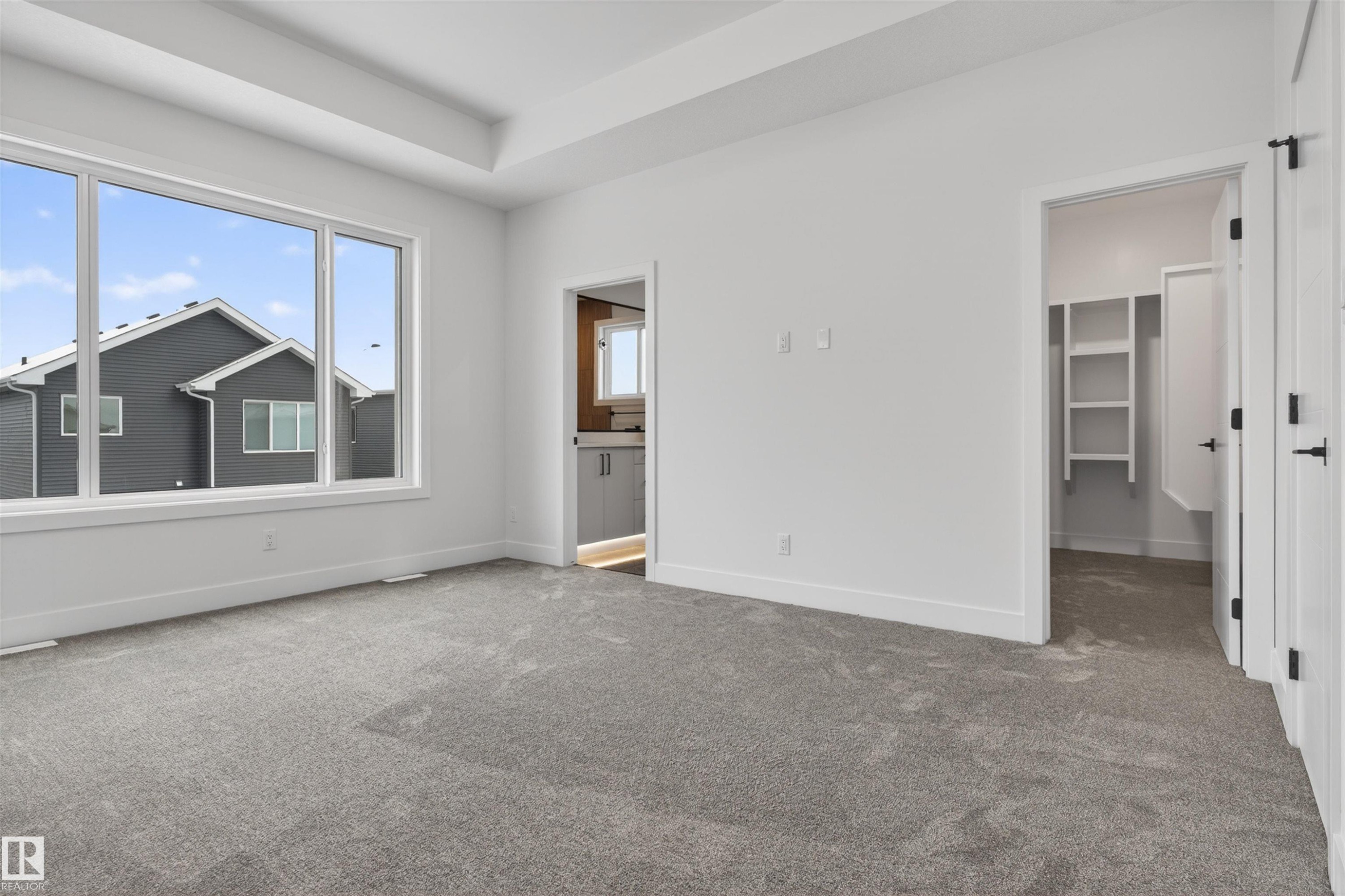 The property features a spacious room with light gray carpeting and a large window providing ample natural light - 11 Redbud Way, St. Albert, AB - Indoor Photo Showing Other Room