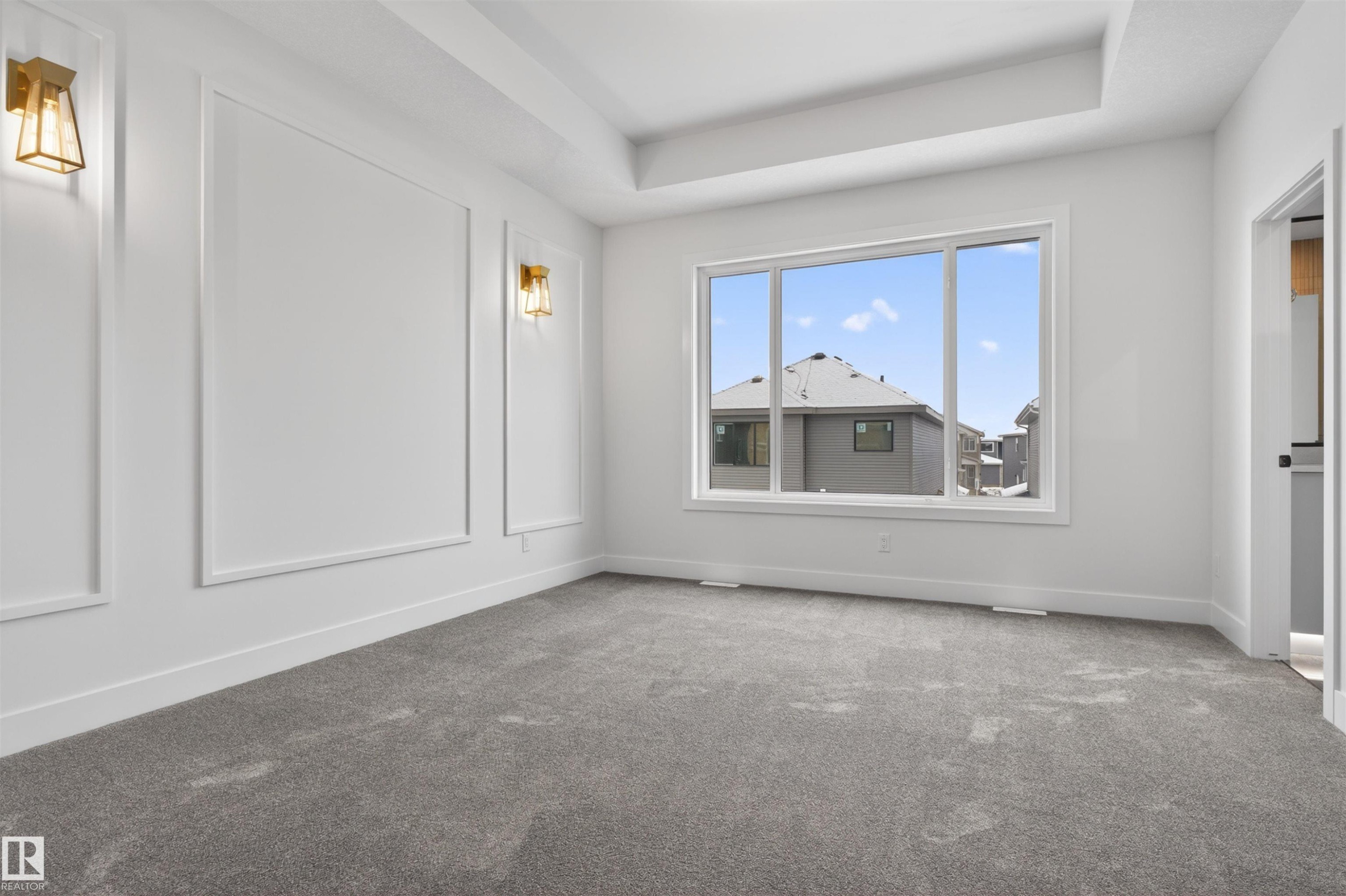 This room features a high tray ceiling, a large window providing natural light, and grey carpet - 11 Redbud Way, St. Albert, AB - Indoor Photo Showing Other Room