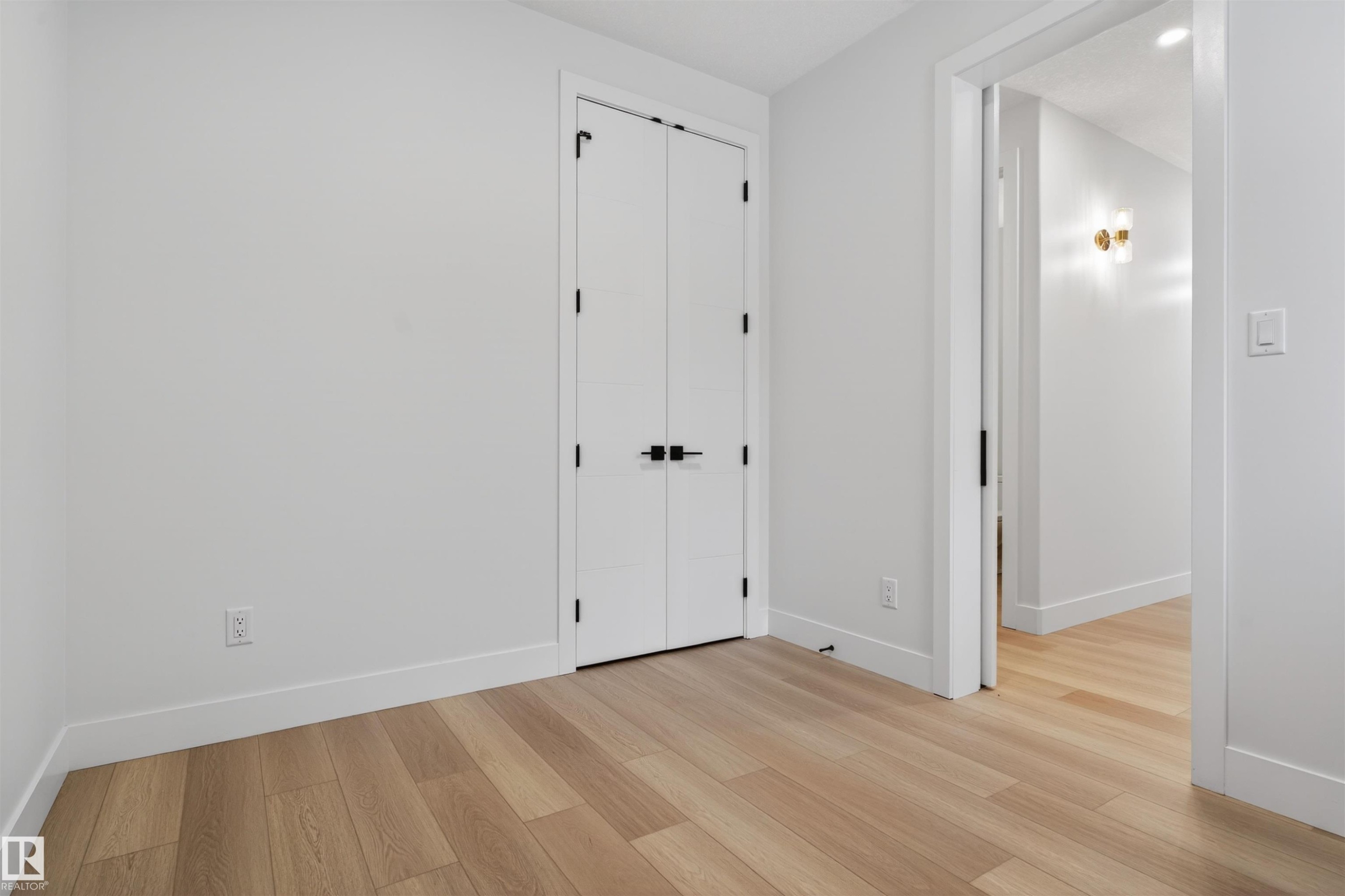 This room features light wood flooring, white walls, and white doors with black hardware - 11 Redbud Way, St. Albert, AB - Indoor Photo Showing Other Room