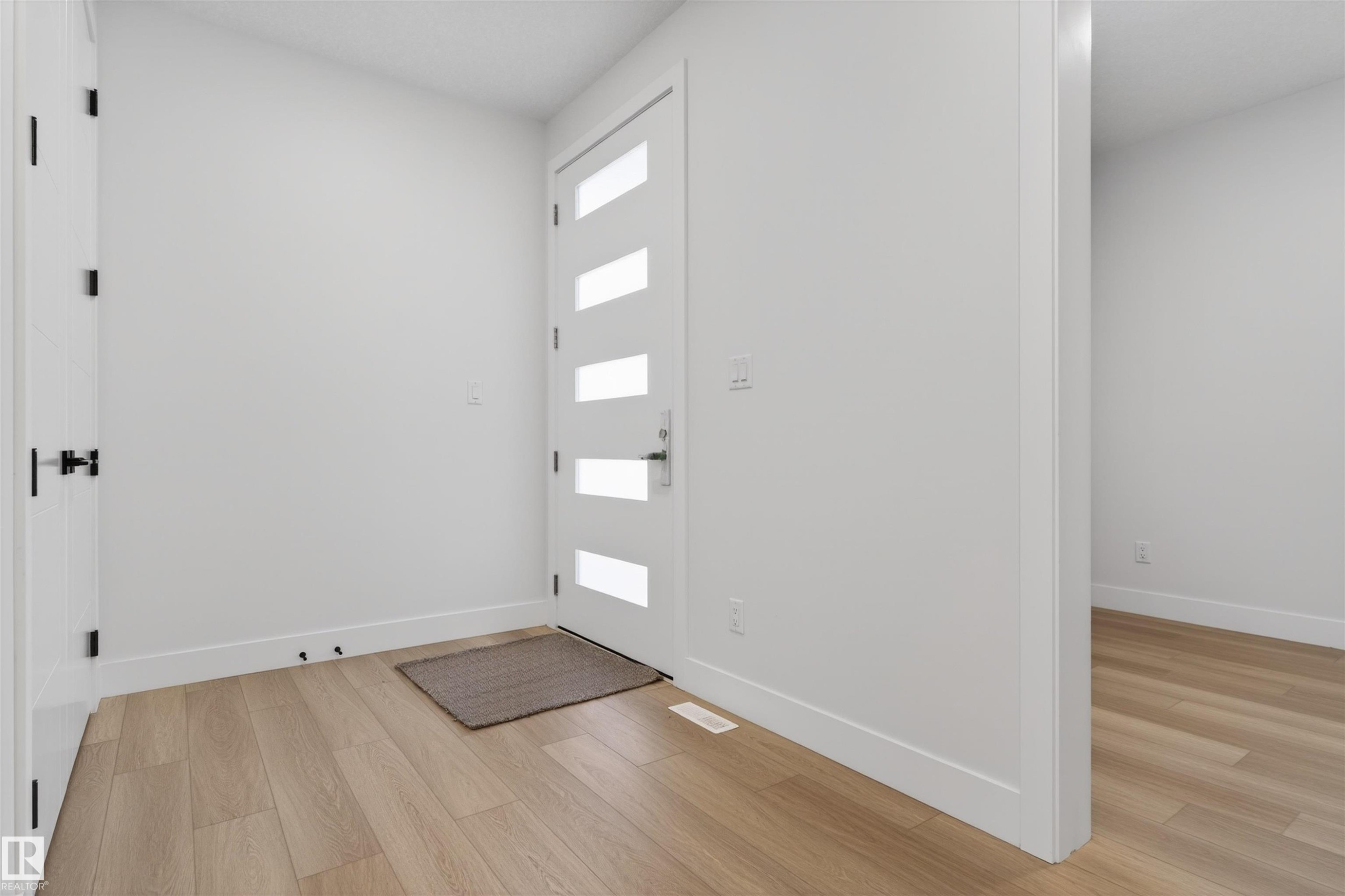 The property features a bright entranceway with light-toned flooring, a modern white door with frosted glass panels, and crisp white walls throughout - 11 Redbud Way, St. Albert, AB - Indoor Photo Showing Other Room