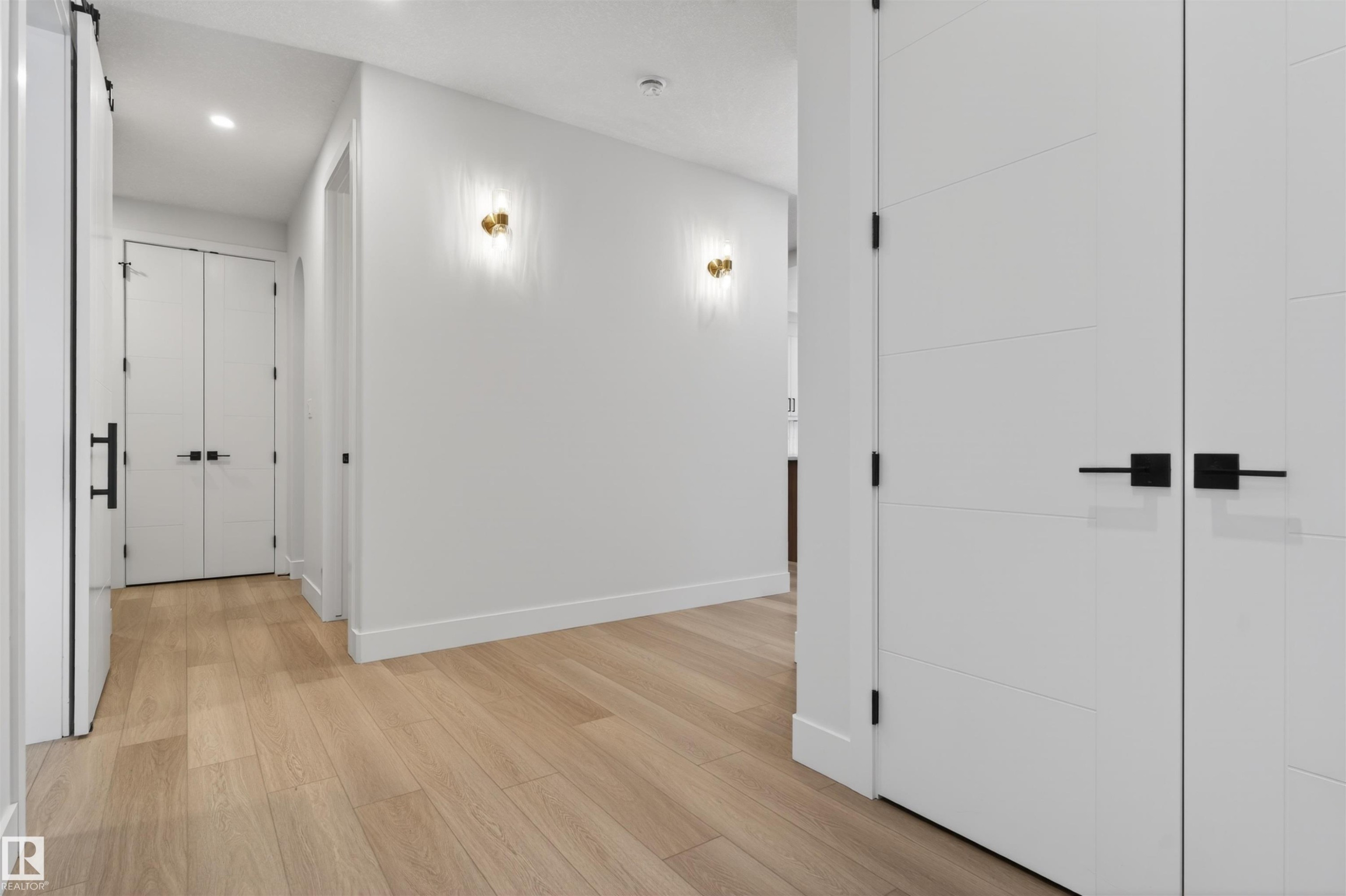 Hallway featuring light-toned hardwood flooring, white walls, and modern wall sconces - 11 Redbud Way, St. Albert, AB - Indoor Photo Showing Other Room
