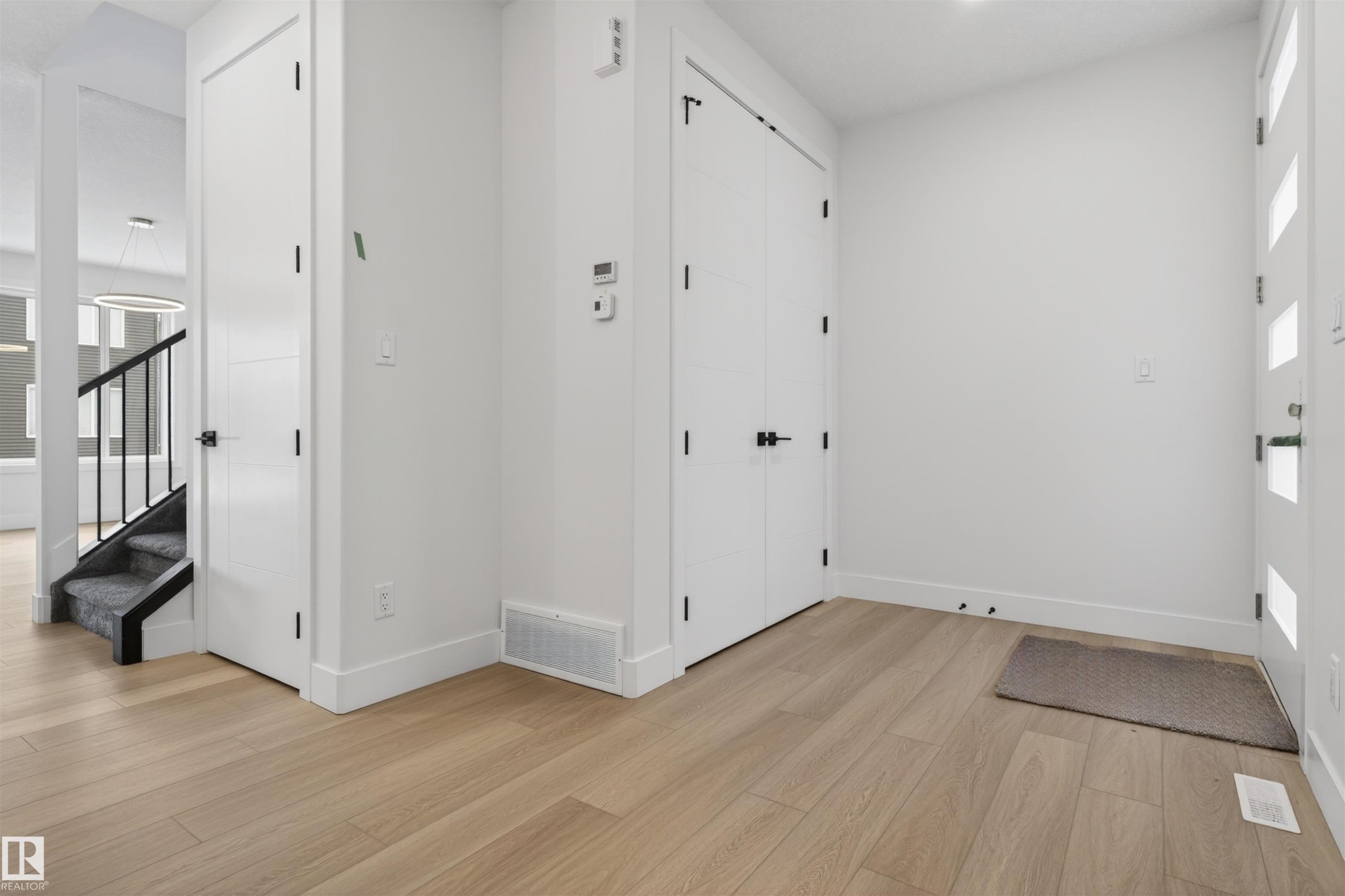 The property features light-toned hardwood flooring, white walls, and white doors with black hardware - 11 Redbud Way, St. Albert, AB - Indoor Photo Showing Other Room