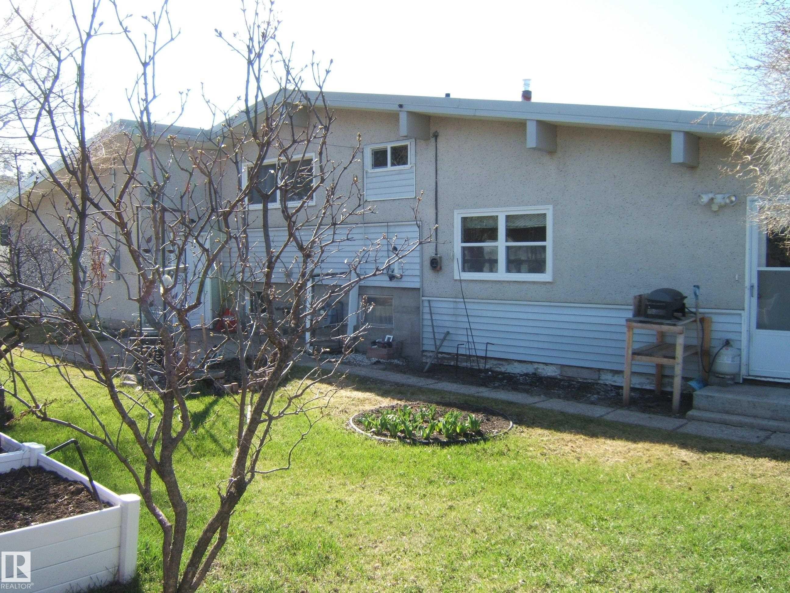 Exterior featuring a stucco and siding finish, white trim windows, and a side entrance door - 4702 52 Avenue, Two Hills, AB - Outdoor