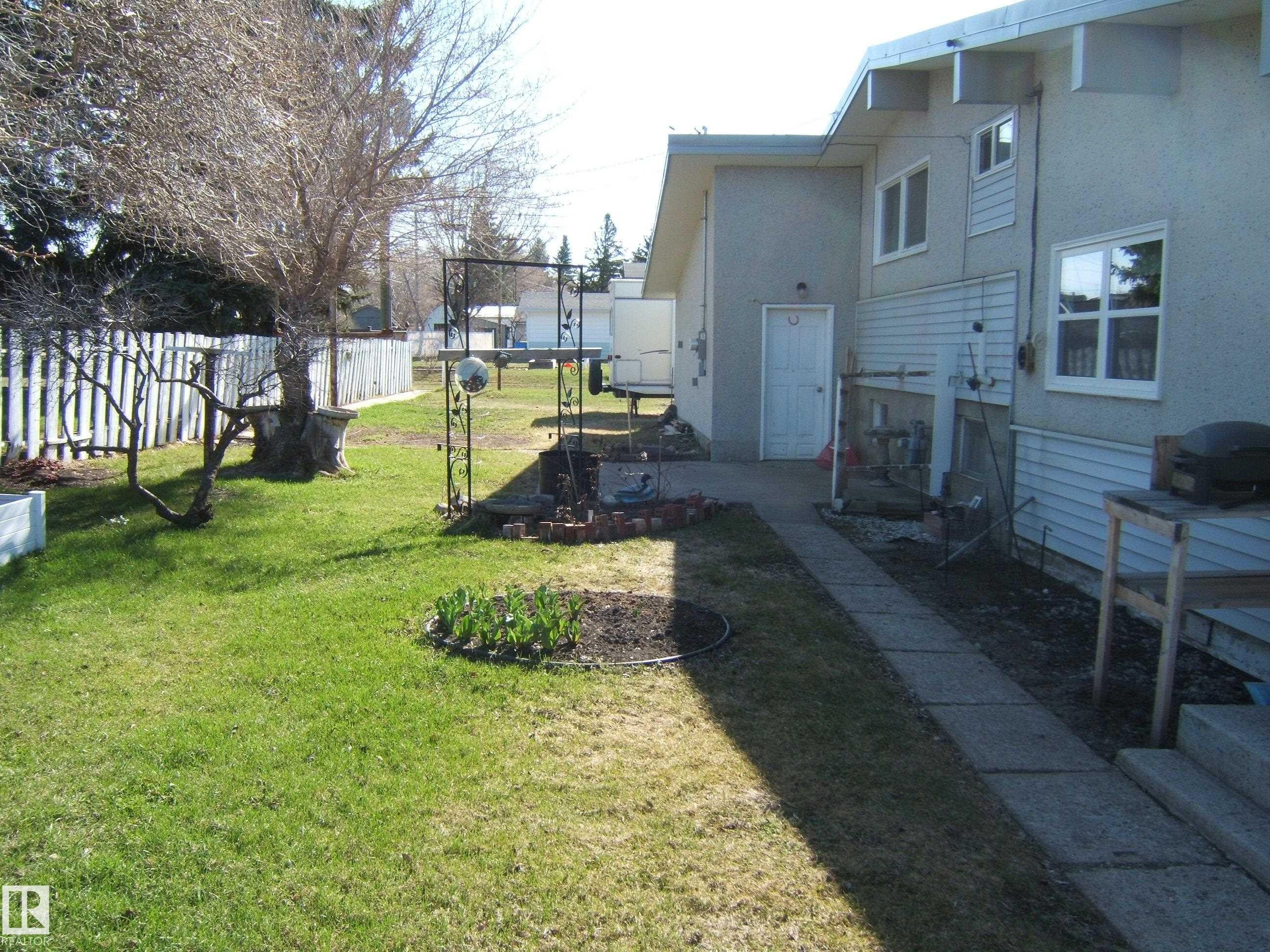 Expansive lawn area featuring a picket fence perimeter - 4702 52 Avenue, Two Hills, AB - Outdoor