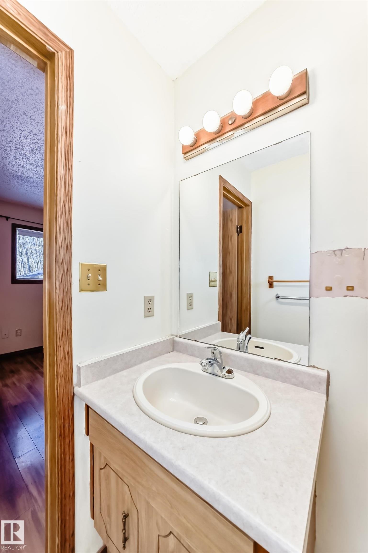 Bathroom vanity with a white countertop and an integrated sink, featuring a mirror and overhead lighting - 100 23016 Twp Rd 504, Rural Leduc County, AB - Indoor Photo Showing Bathroom