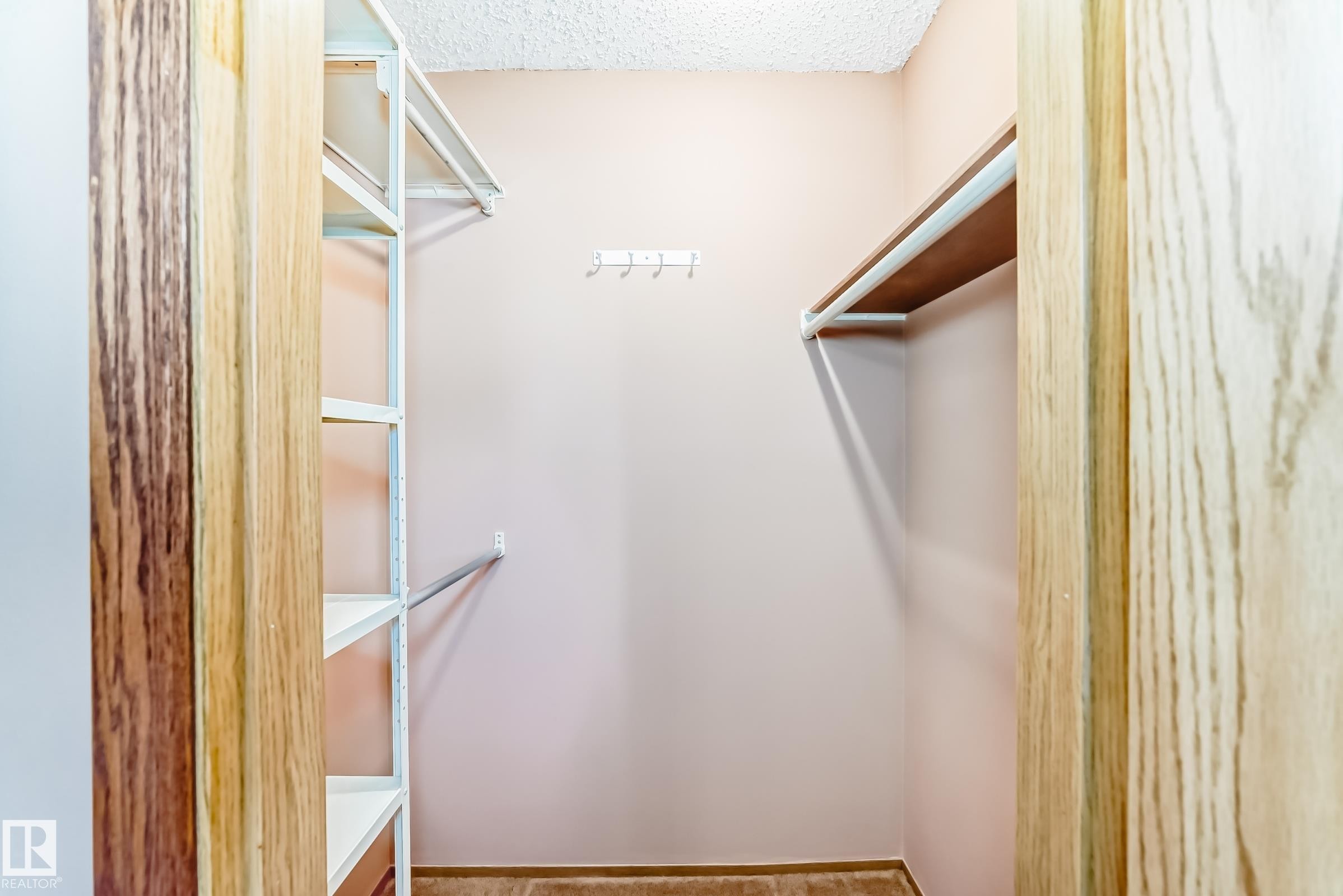 Walk-in closet featuring built-in shelving, a hanging rod, and wall-mounted hooks - 100 23016 Twp Rd 504, Rural Leduc County, AB - Indoor