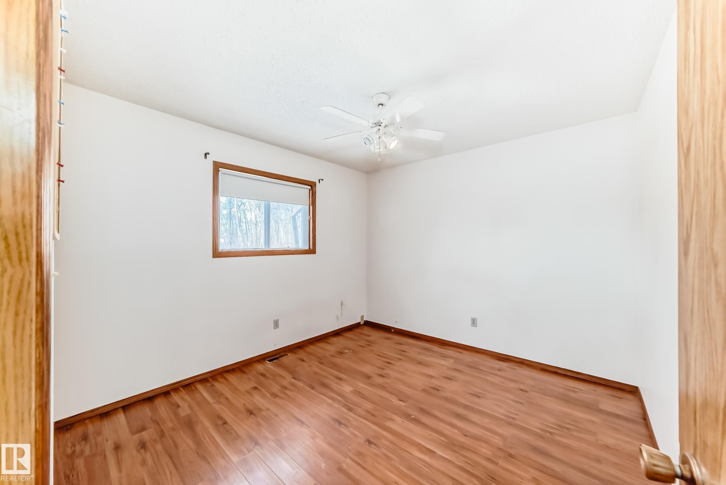 This room features hardwood flooring, white walls, and a window with a wooden frame - 100 23016 Twp Rd 504, Rural Leduc County, AB - Indoor Photo Showing Other Room