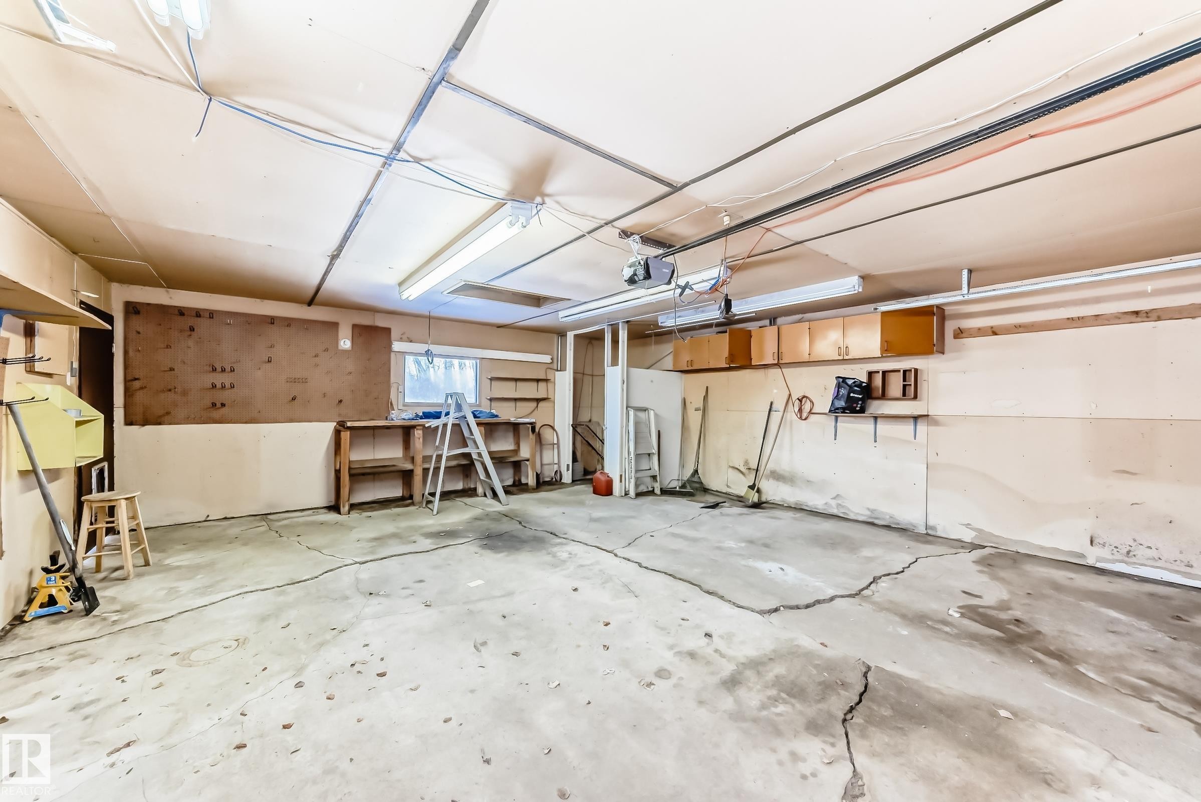 The property includes a spacious garage with a concrete floor, built-in shelving, and overhead lighting - 100 23016 Twp Rd 504, Rural Leduc County, AB - Indoor Photo Showing Garage