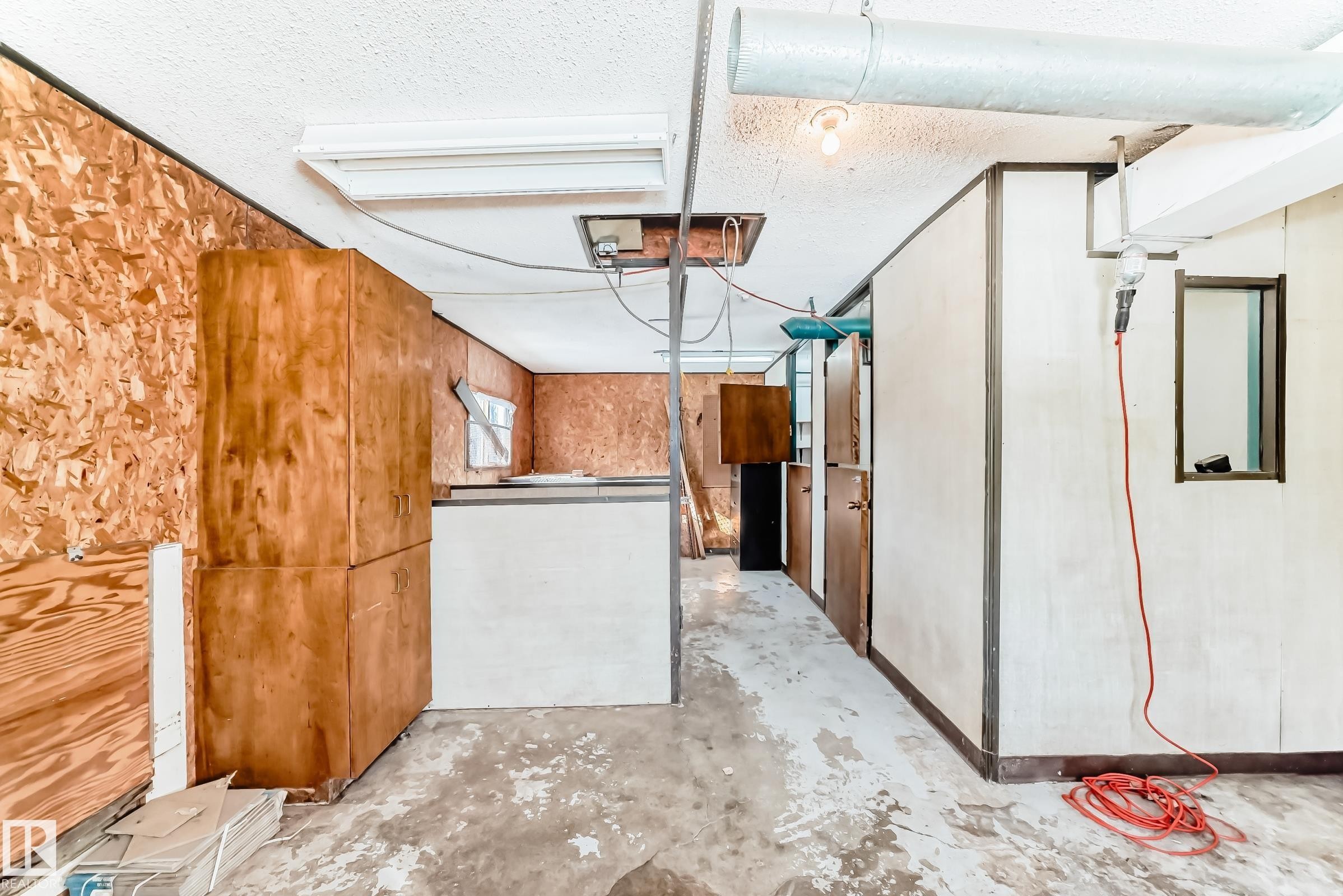 The property features exposed ceiling ductwork, a fluorescent light fixture, and an unfinished floor - 100 23016 Twp Rd 504, Rural Leduc County, AB - Indoor Photo Showing Other Room