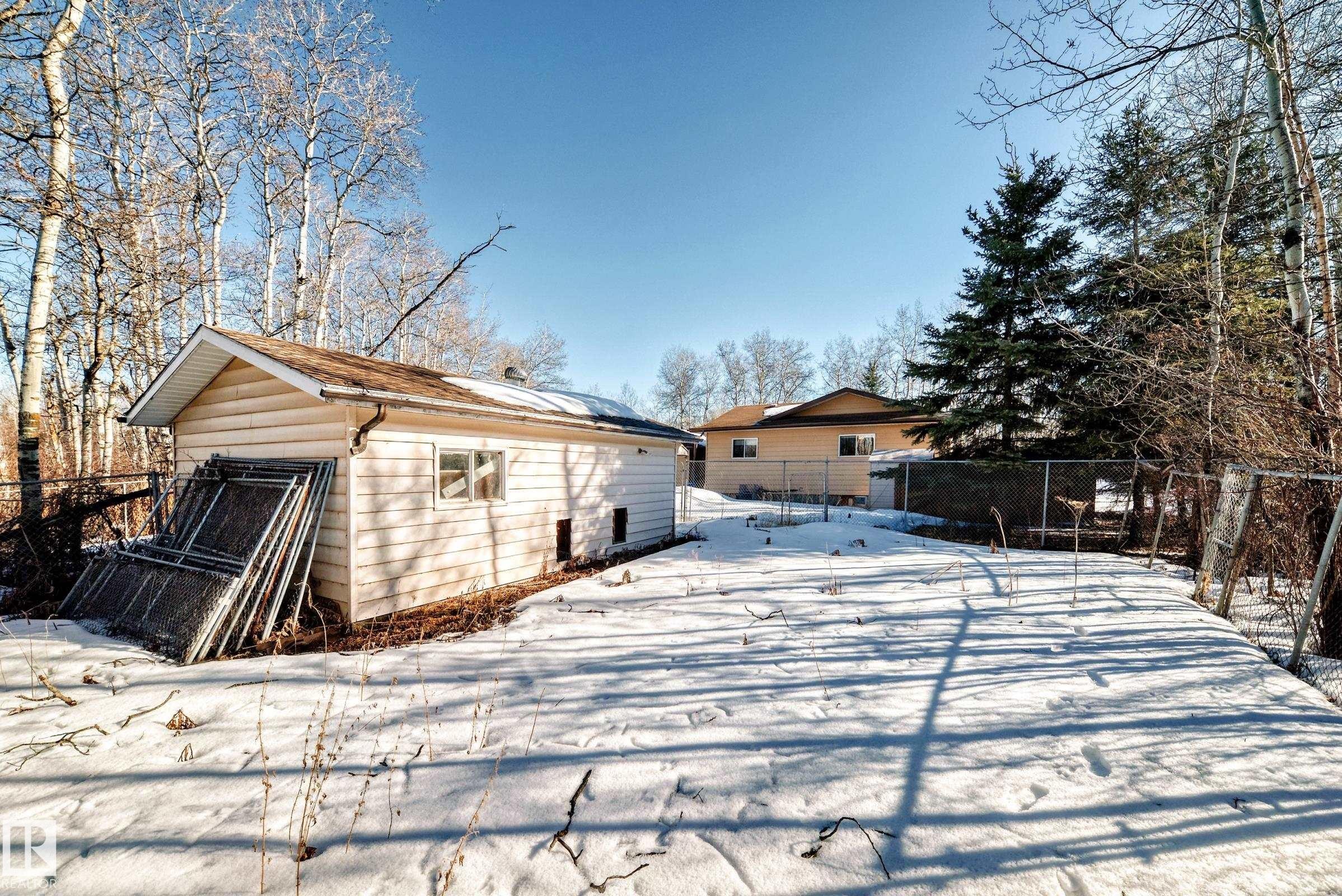 The property includes a detached outbuilding with light-colored siding, a brown roof, and a visible window - 100 23016 Twp Rd 504, Rural Leduc County, AB - Outdoor