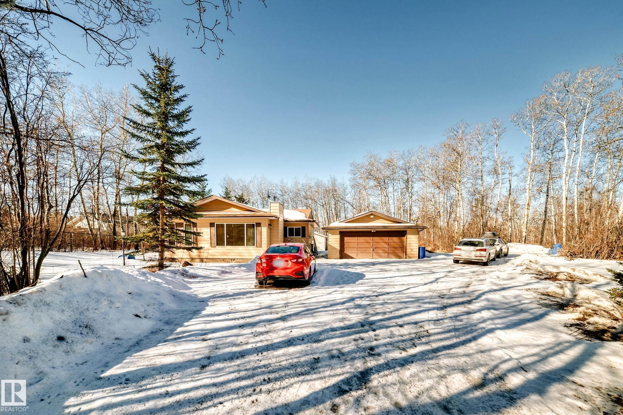 The property features a single-story residence with a light-colored exterior and a brown roof - 100 23016 Twp Rd 504, Rural Leduc County, AB - Outdoor