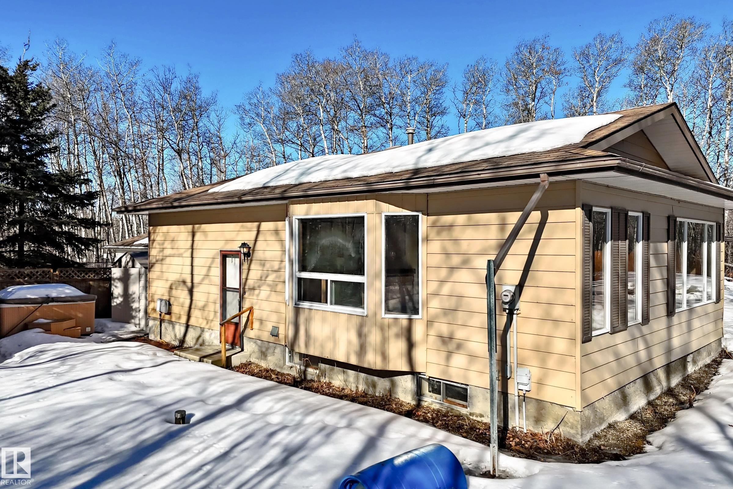 The property features exterior siding, a shingled roof, and multiple windows, including a large picture window - 100 23016 Twp Rd 504, Rural Leduc County, AB - Outdoor