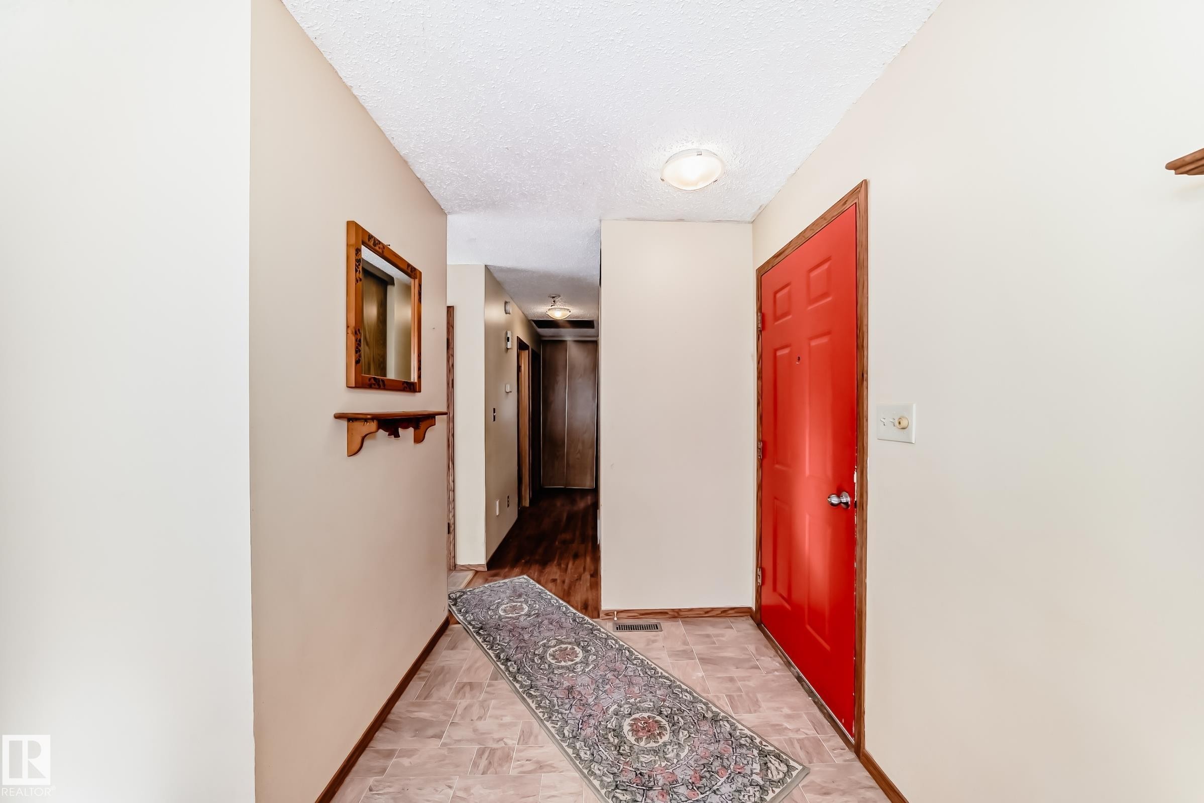 The property's entryway features a red door, light-colored walls, and tile flooring - 100 23016 Twp Rd 504, Rural Leduc County, AB - Indoor Photo Showing Other Room