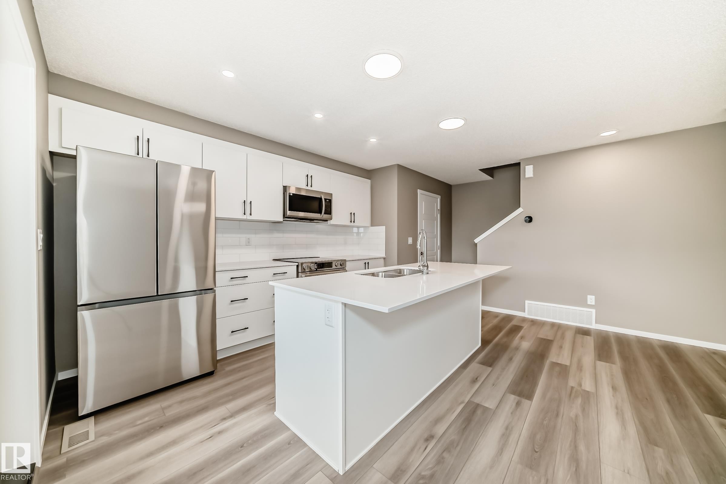 Contemporary kitchen featuring an island with an undermount sink and white countertops - 20415 16 Avenue, Edmonton, AB
