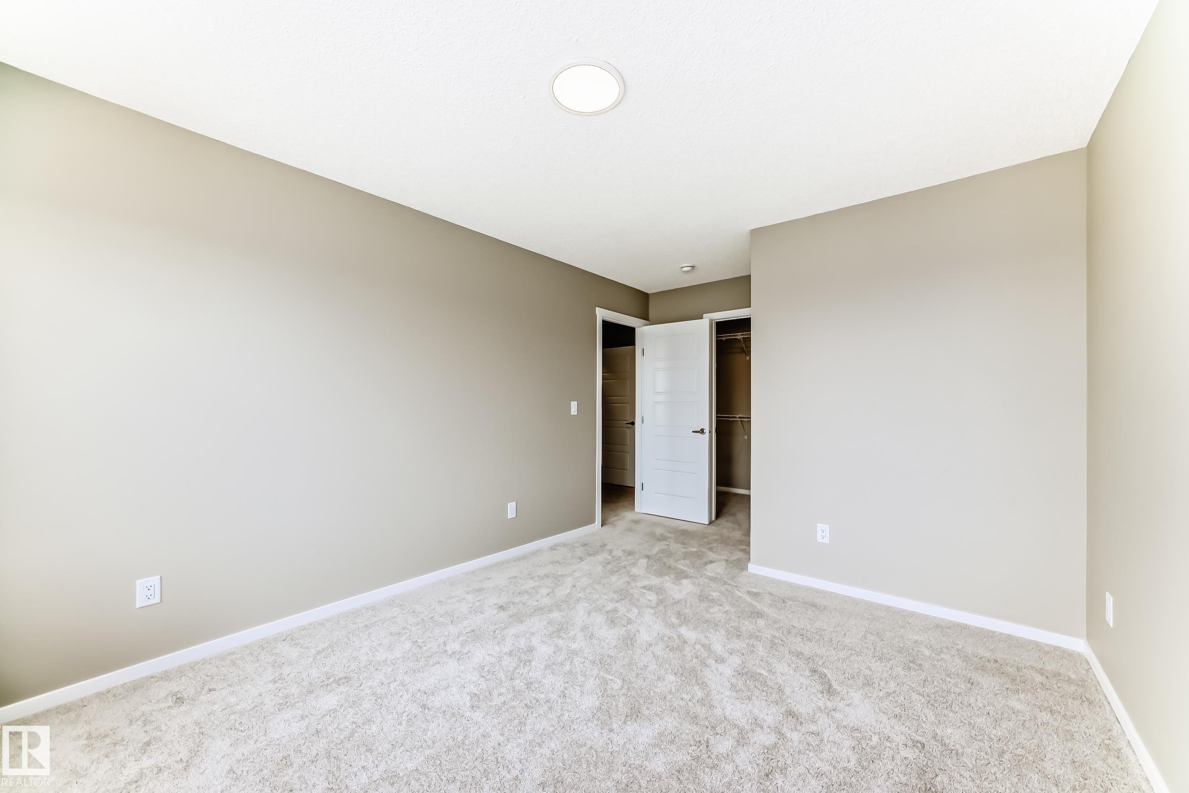 Neutral-toned room featuring light-colored carpeting, white baseboards, and a recessed ceiling light fixture - 20415 16 Avenue, Edmonton, AB