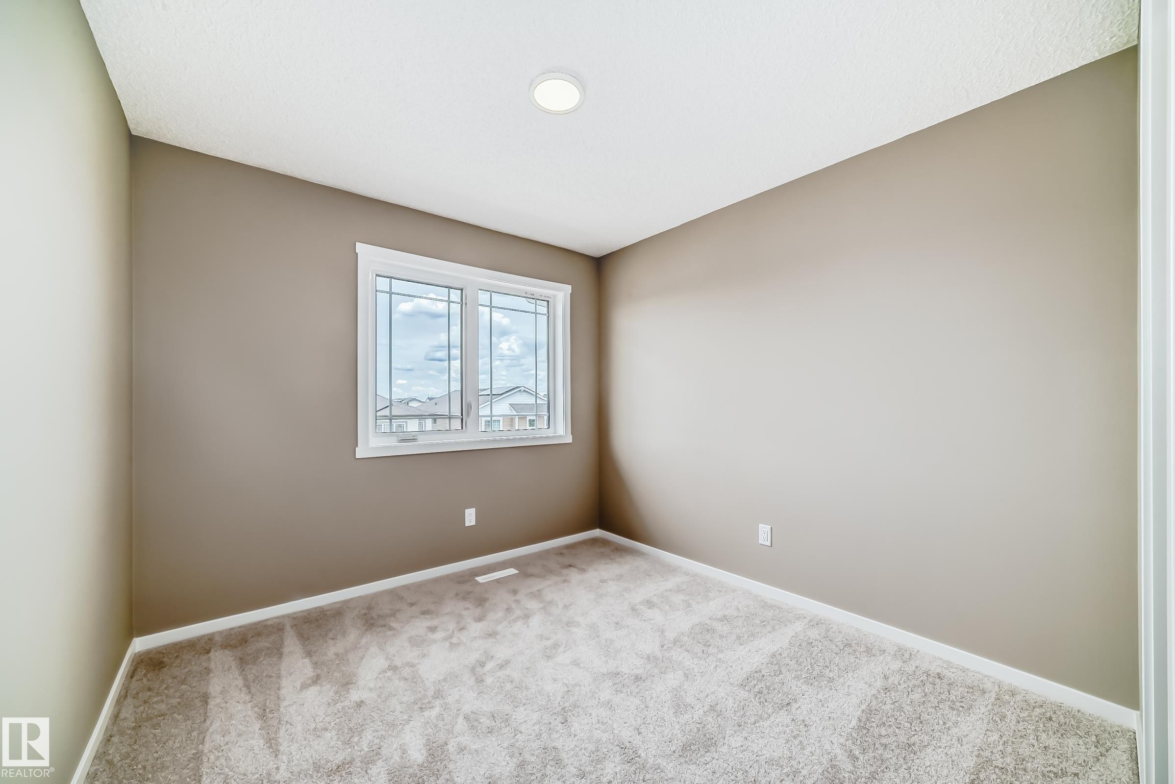 Room featuring neutral-toned walls, white trim, and a window with divided lites - 20415 16 Avenue, Edmonton, AB