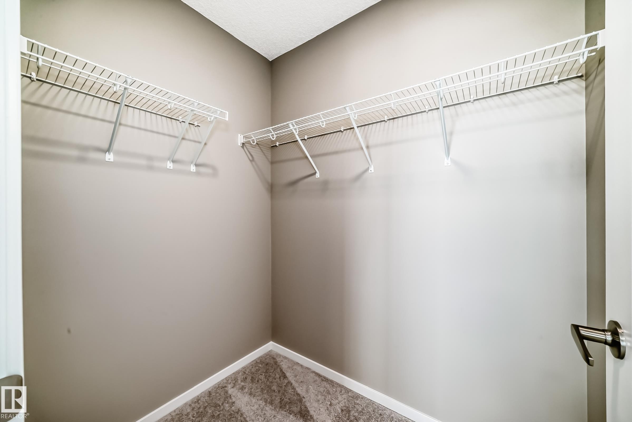 Walk-in closet featuring neutral-toned walls, white wire shelving, white baseboards, and patterned carpet - 20415 16 Avenue, Edmonton, AB