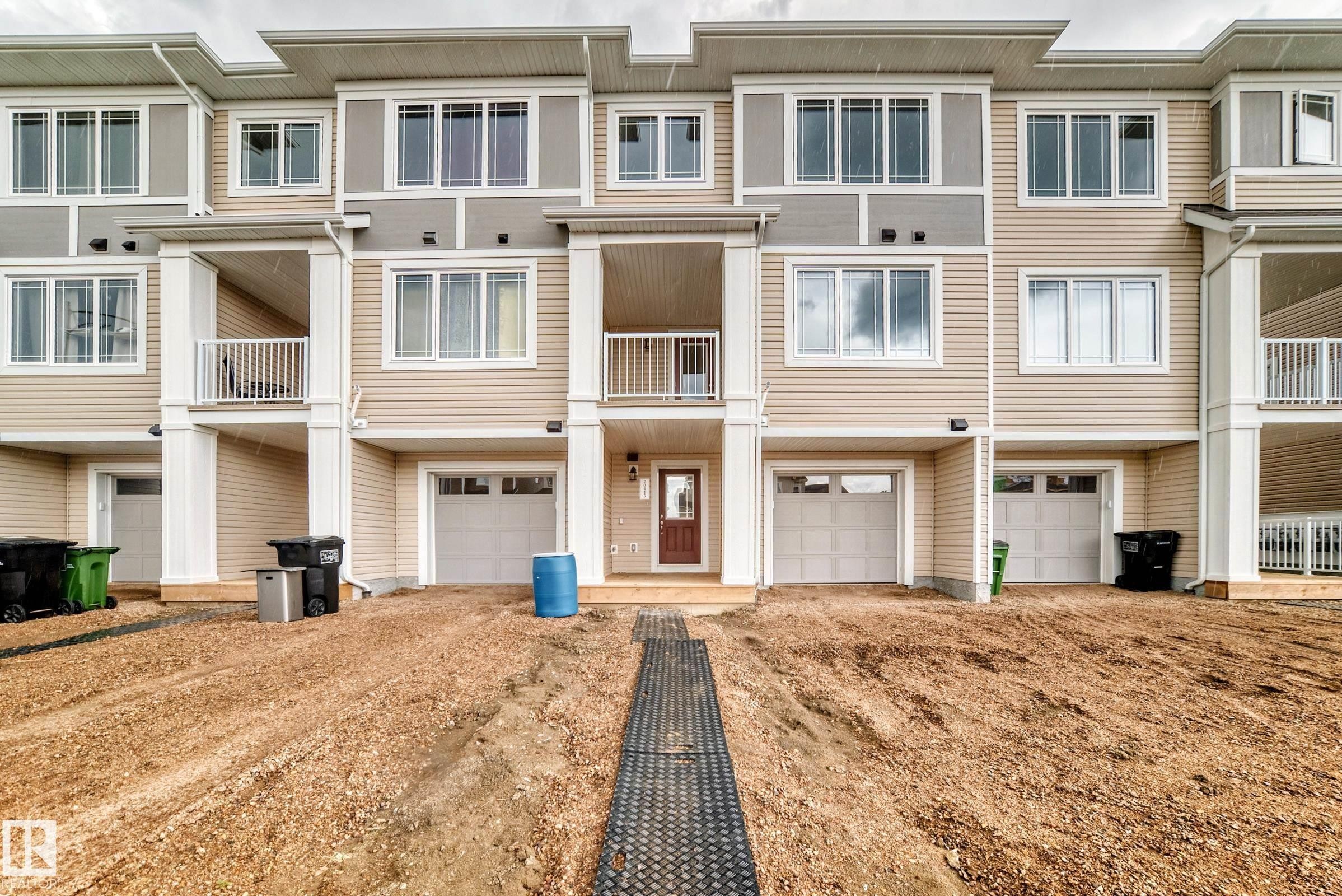 Modern multi-story facade featuring light beige siding and white trim - 20415 16 Avenue, Edmonton, AB