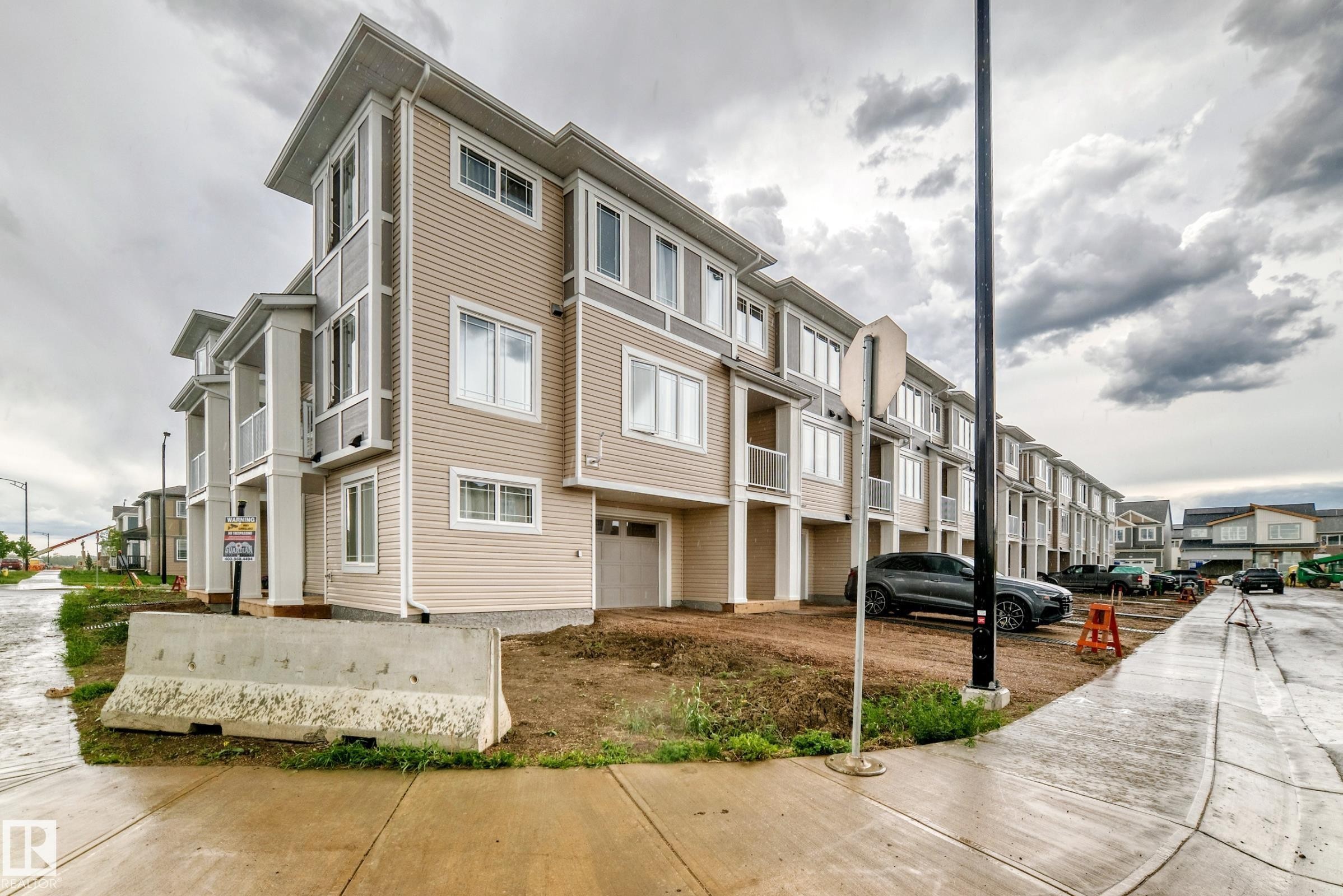 Contemporary multi-level townhome featuring a beige siding exterior with white trim, a private garage, and multiple balconies - 20415 16 Avenue, Edmonton, AB