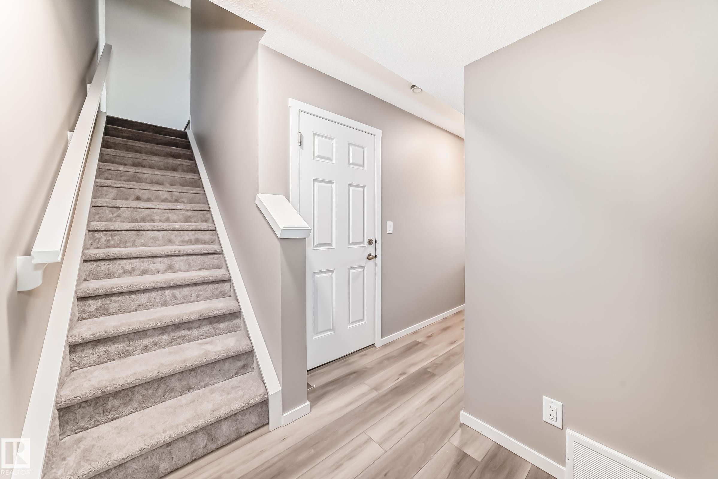 Carpeted staircase with white handrail and trim, contrasting with light wood-finish flooring - 20415 16 Avenue, Edmonton, AB