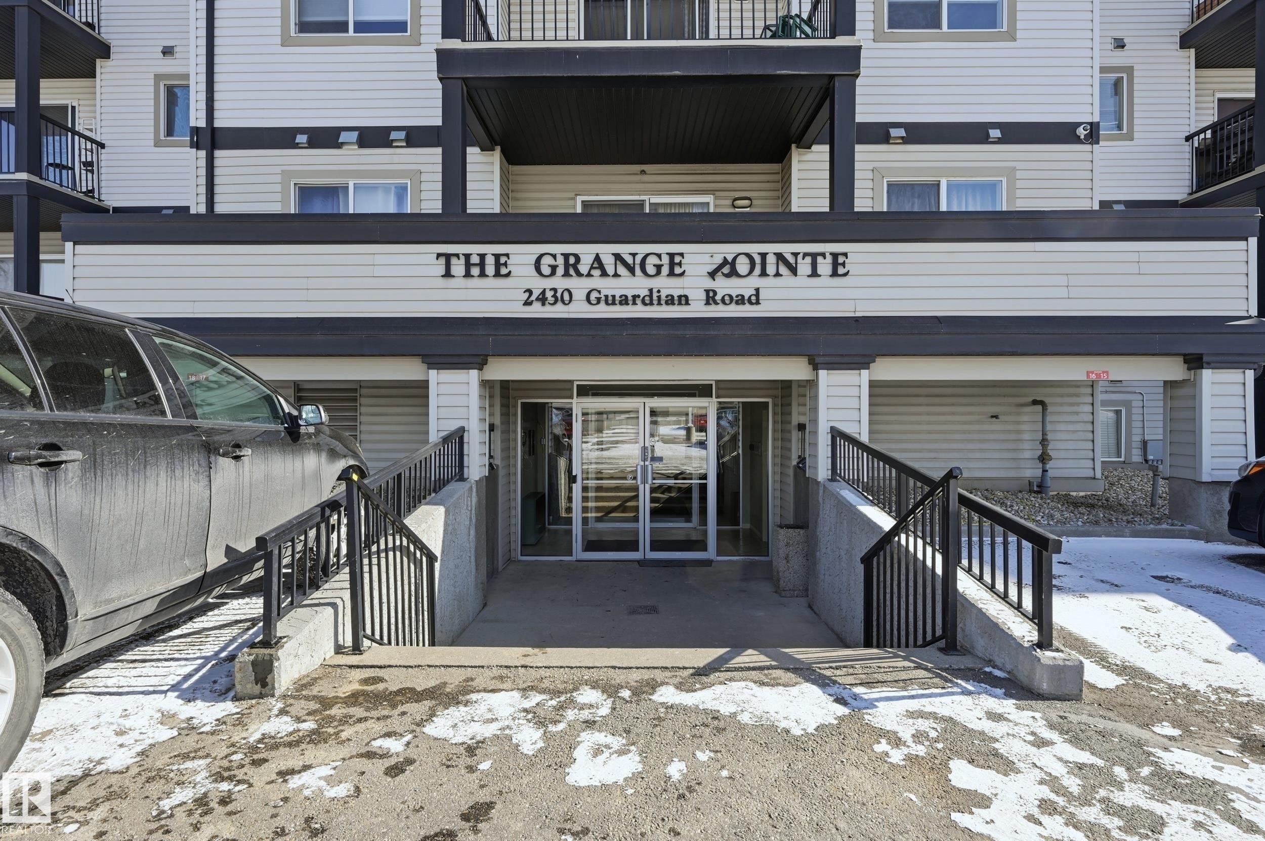 The property features a building entrance with glass doors, exterior steps, and handrails - 314 2430 Guardian Road, Edmonton, AB - Outdoor With Balcony