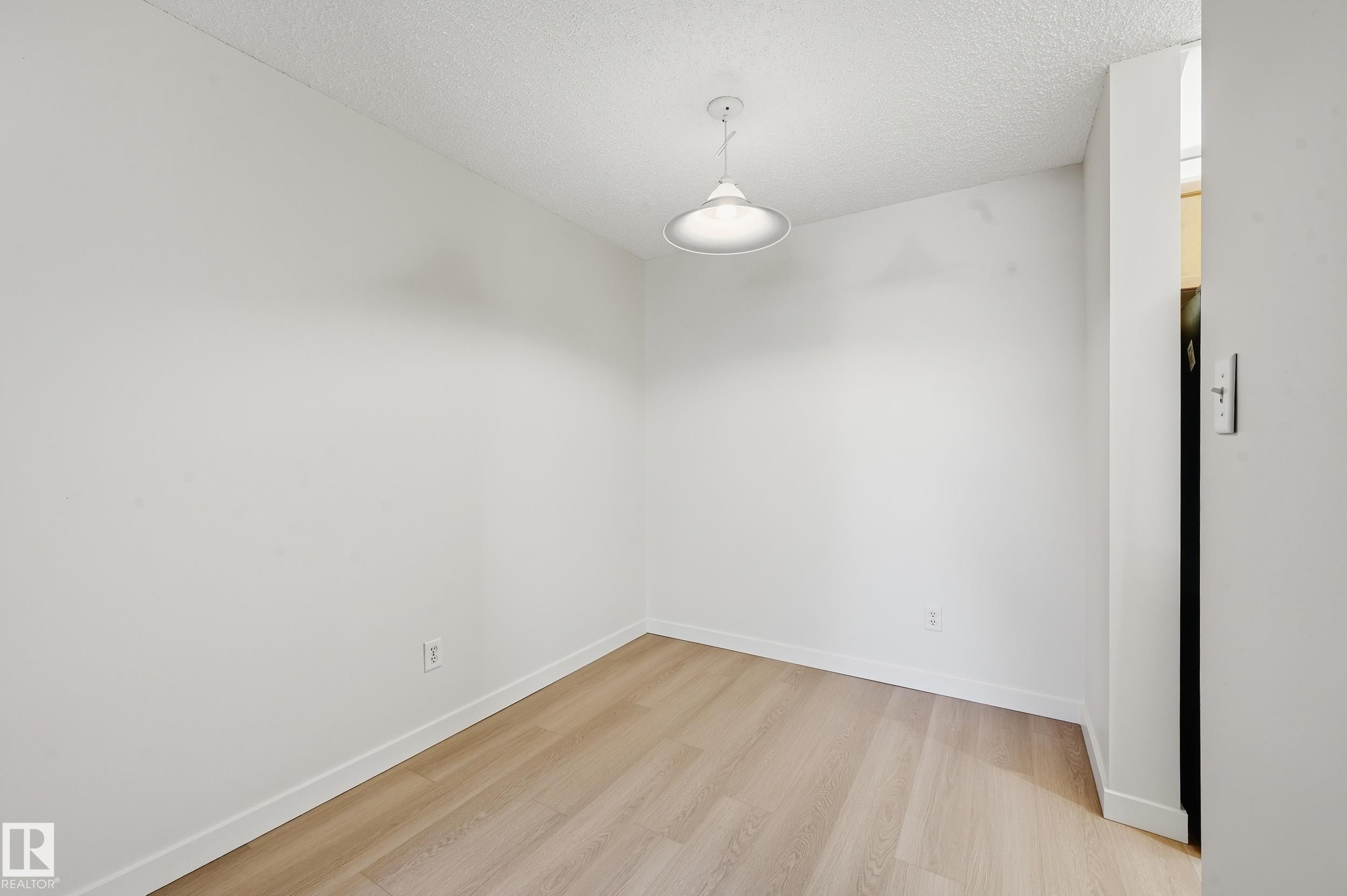 This versatile room features light-toned flooring, white walls, and a modern ceiling light fixture - 314 2430 Guardian Road, Edmonton, AB - Indoor Photo Showing Other Room