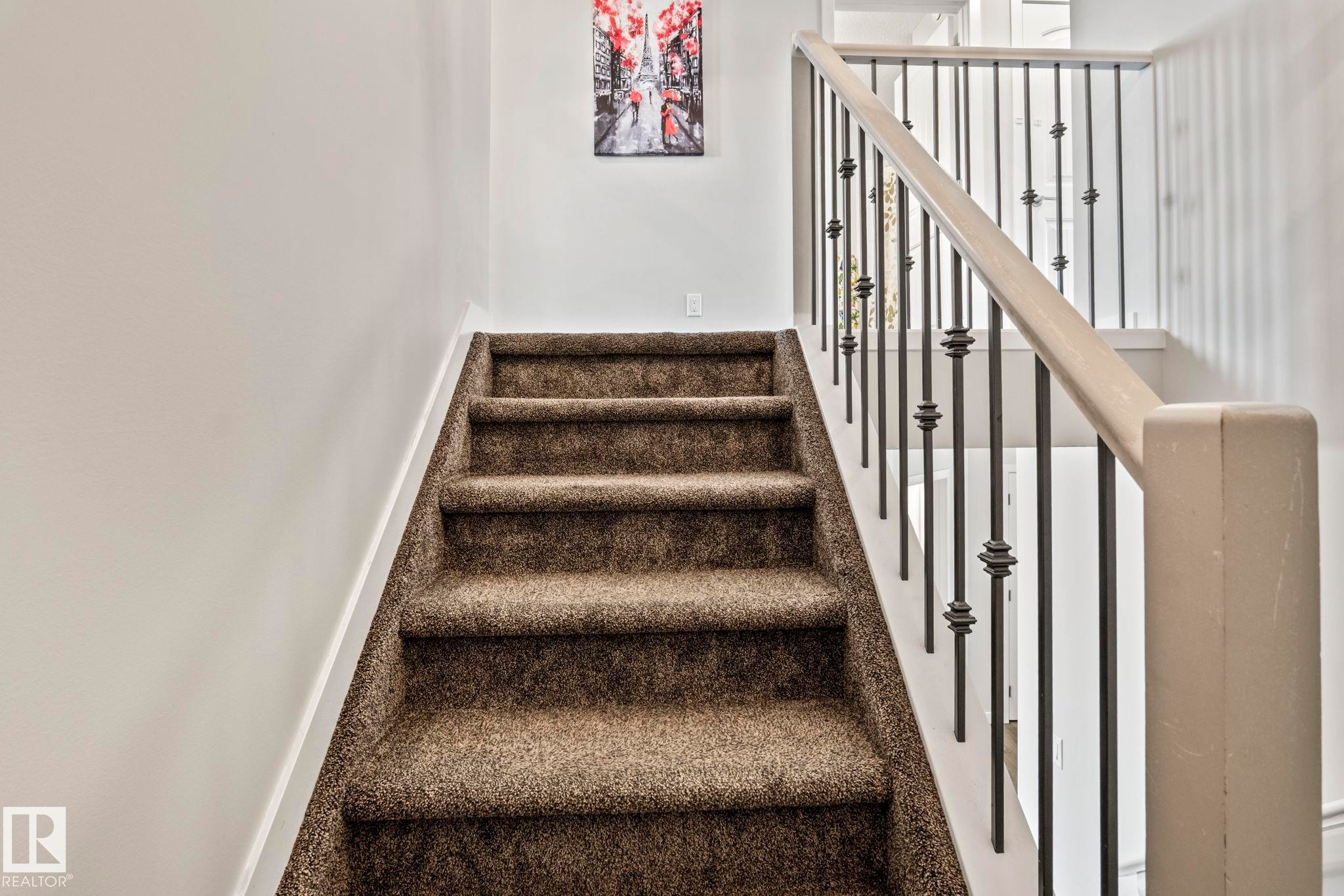 The staircase features carpeted steps and a railing with metal balusters - 483 Ebbers Way Nw, Edmonton, AB - Indoor Photo Showing Other Room