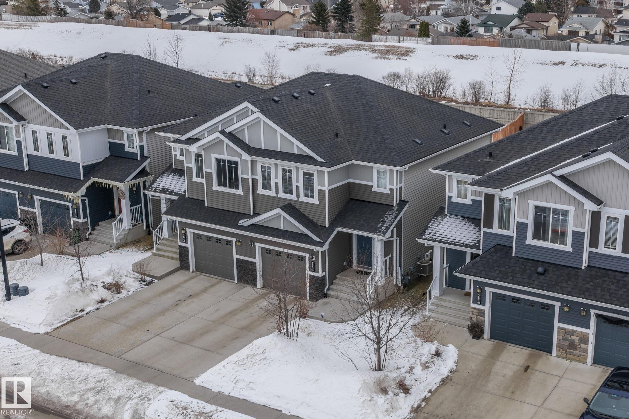 This property features a two-story exterior with a dark shingled roof, light grey siding, and contrasting dark accents - 483 Ebbers Way Nw, Edmonton, AB - Outdoor With Facade