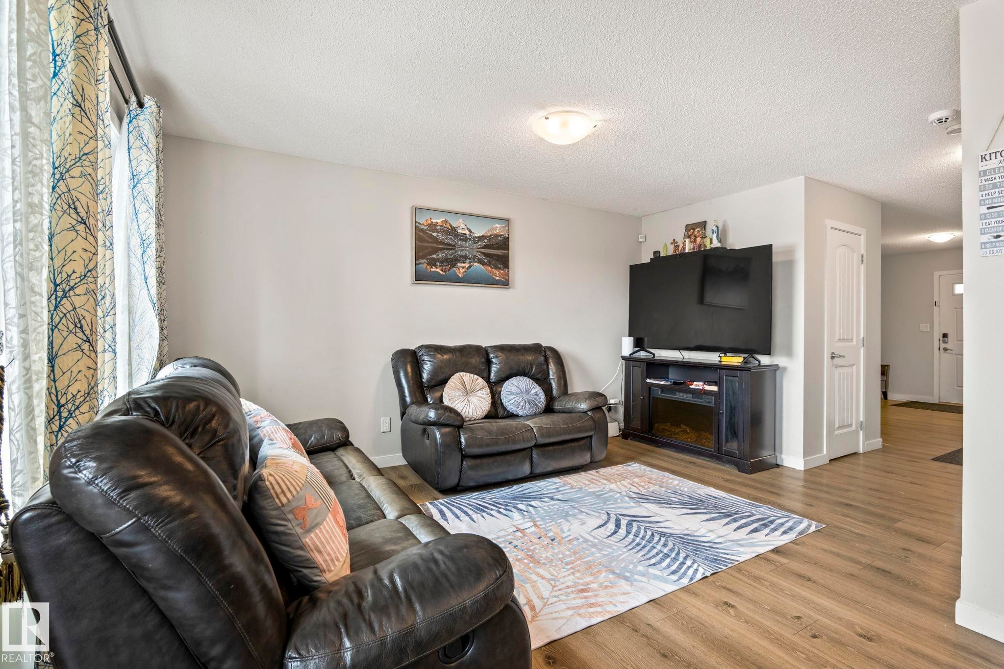 Inviting living area featuring light-colored walls, wood-look flooring, and a decorative area rug - 483 Ebbers Way Nw, Edmonton, AB - Indoor Photo Showing Living Room