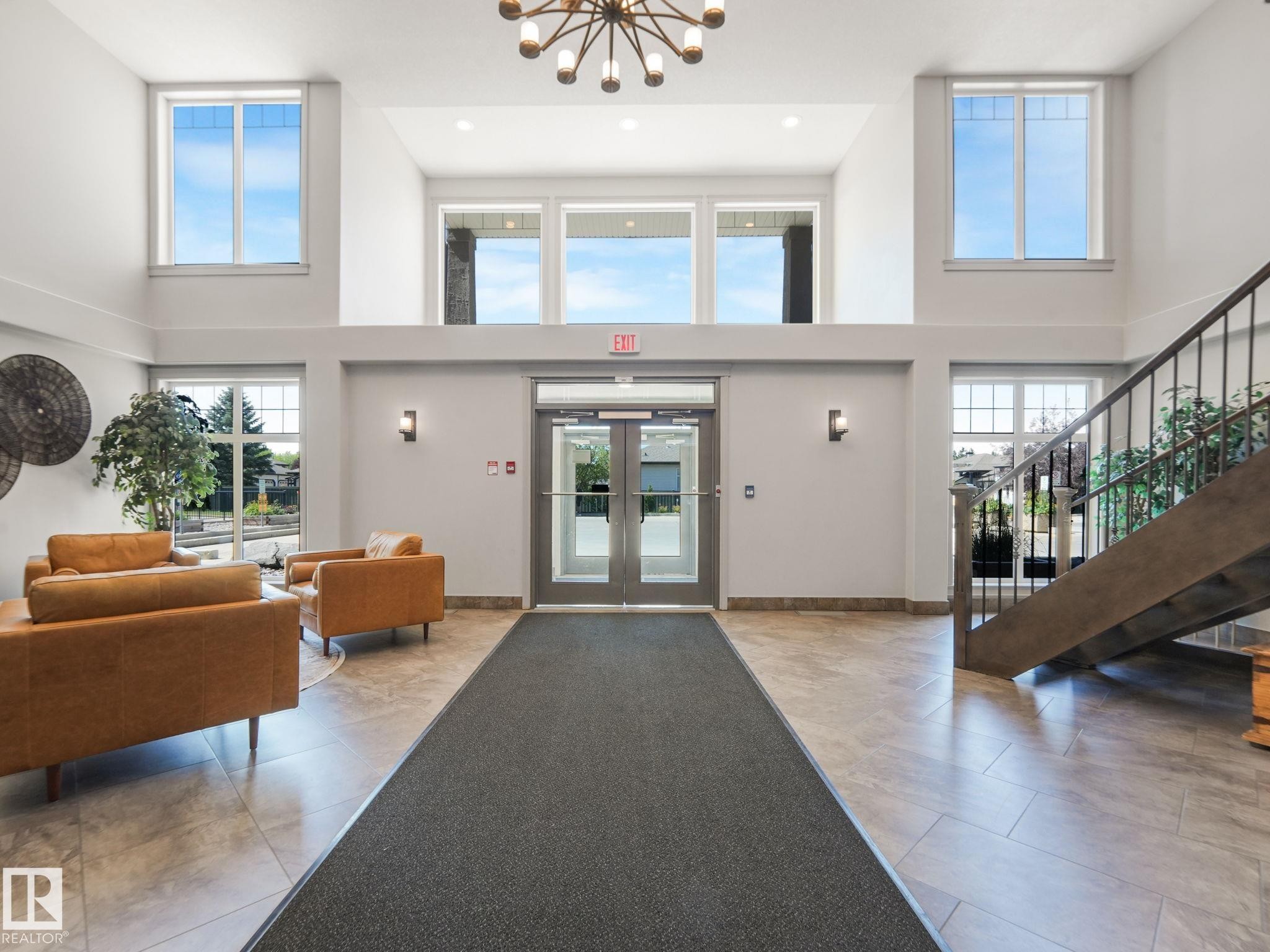 Inviting entrance area with high ceilings, large windows, and tiled flooring - 412 12408 15 Avenue, Edmonton, AB - Indoor Photo Showing Other Room