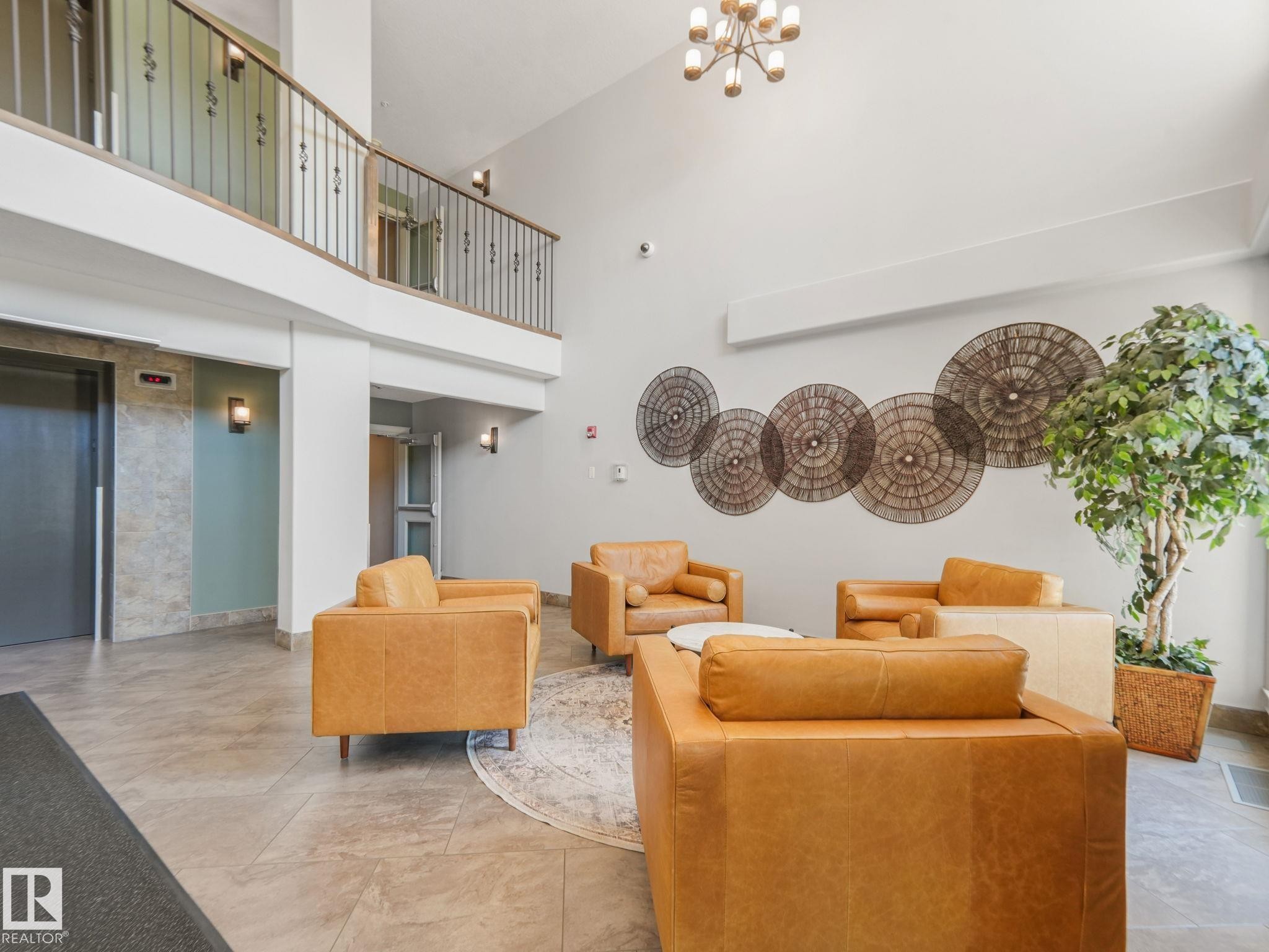 Inviting lobby area with a high ceiling, light-colored walls, and tiled flooring - 412 12408 15 Avenue, Edmonton, AB - Indoor