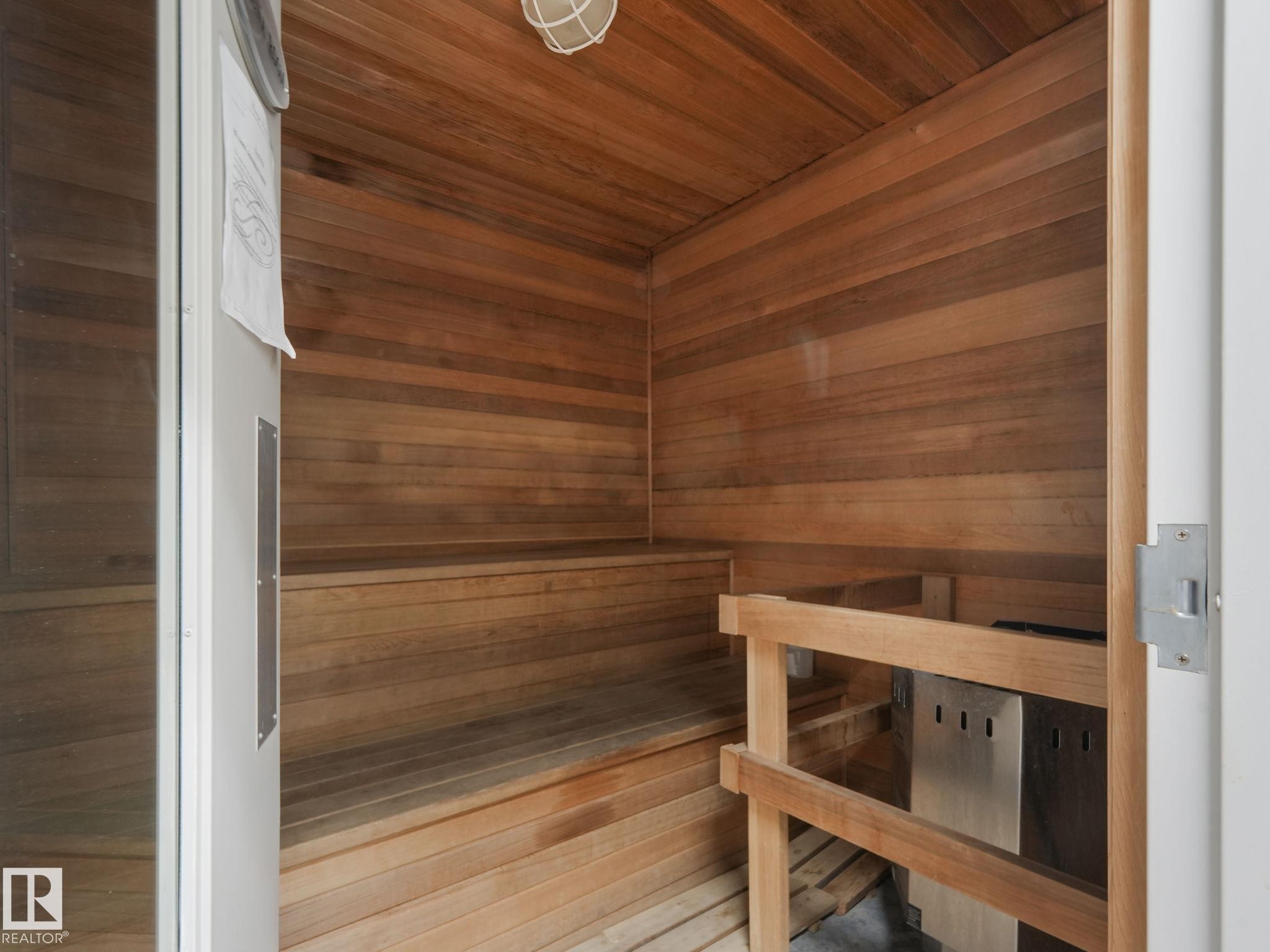 The property includes a sauna with extensive wood paneling and wood benches, featuring a metal heater unit - 412 12408 15 Avenue, Edmonton, AB - Indoor Photo Showing Other Room