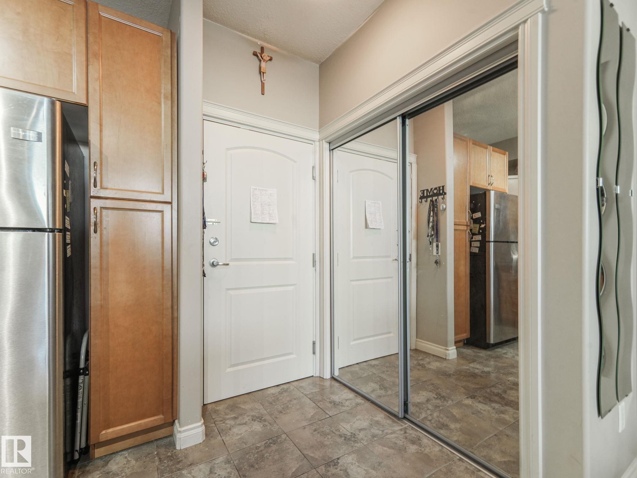 Entryway featuring tiled flooring, a white paneled door, and a mirrored closet with sliding doors - 412 12408 15 Avenue, Edmonton, AB - Indoor Photo Showing Other Room