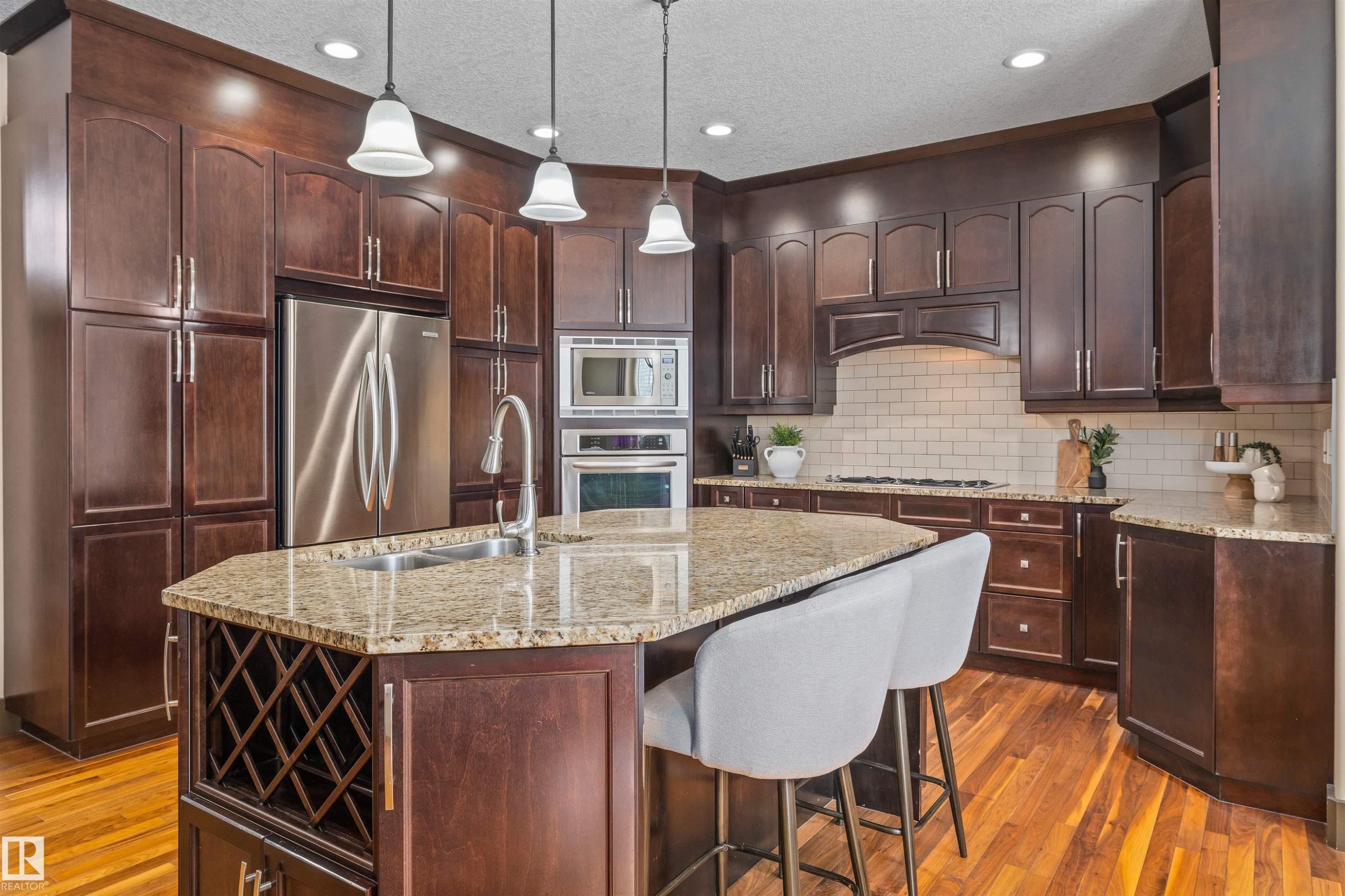 The kitchen features rich wood cabinetry, stainless steel appliances, and a central island with a granite countertop and integrated sink - 1014 Hope Road, Edmonton, AB - Indoor Photo Showing Kitchen With Double Sink With Upgraded Kitchen