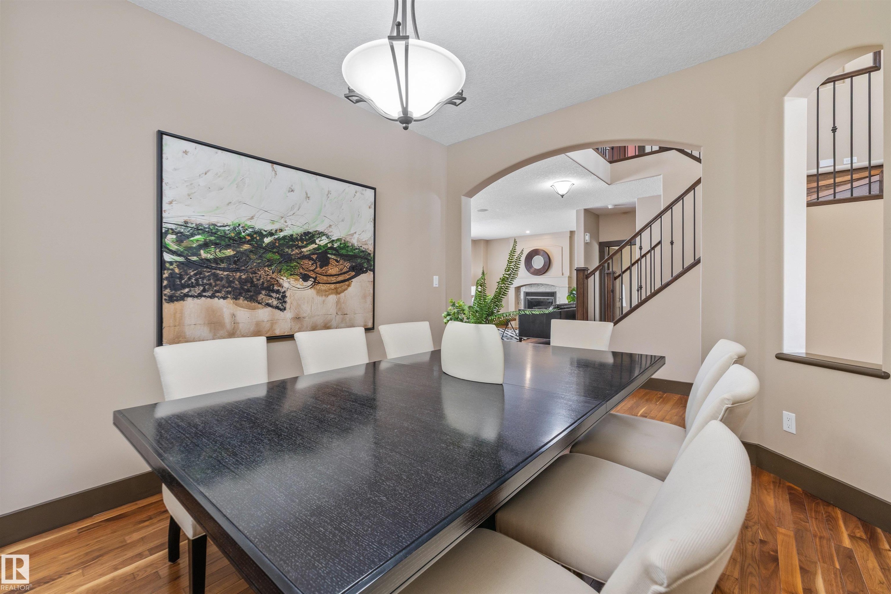 This inviting dining area features hardwood floors, an arched doorway, and a chandelier, creating an elegant atmosphere - 1014 Hope Road, Edmonton, AB - Indoor Photo Showing Dining Room