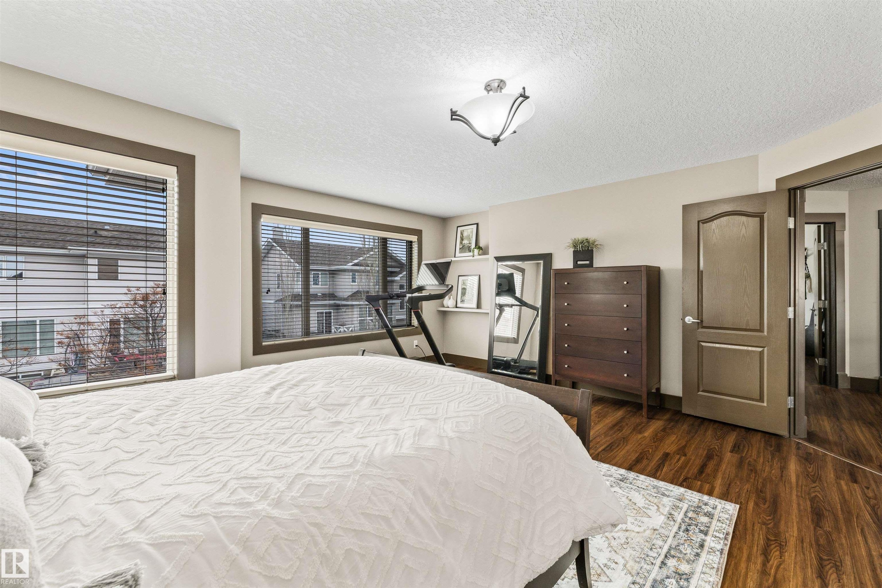 The primary bedroom features wood-style flooring, light-colored walls, and two windows with blinds - 1014 Hope Road, Edmonton, AB - Indoor Photo Showing Bedroom