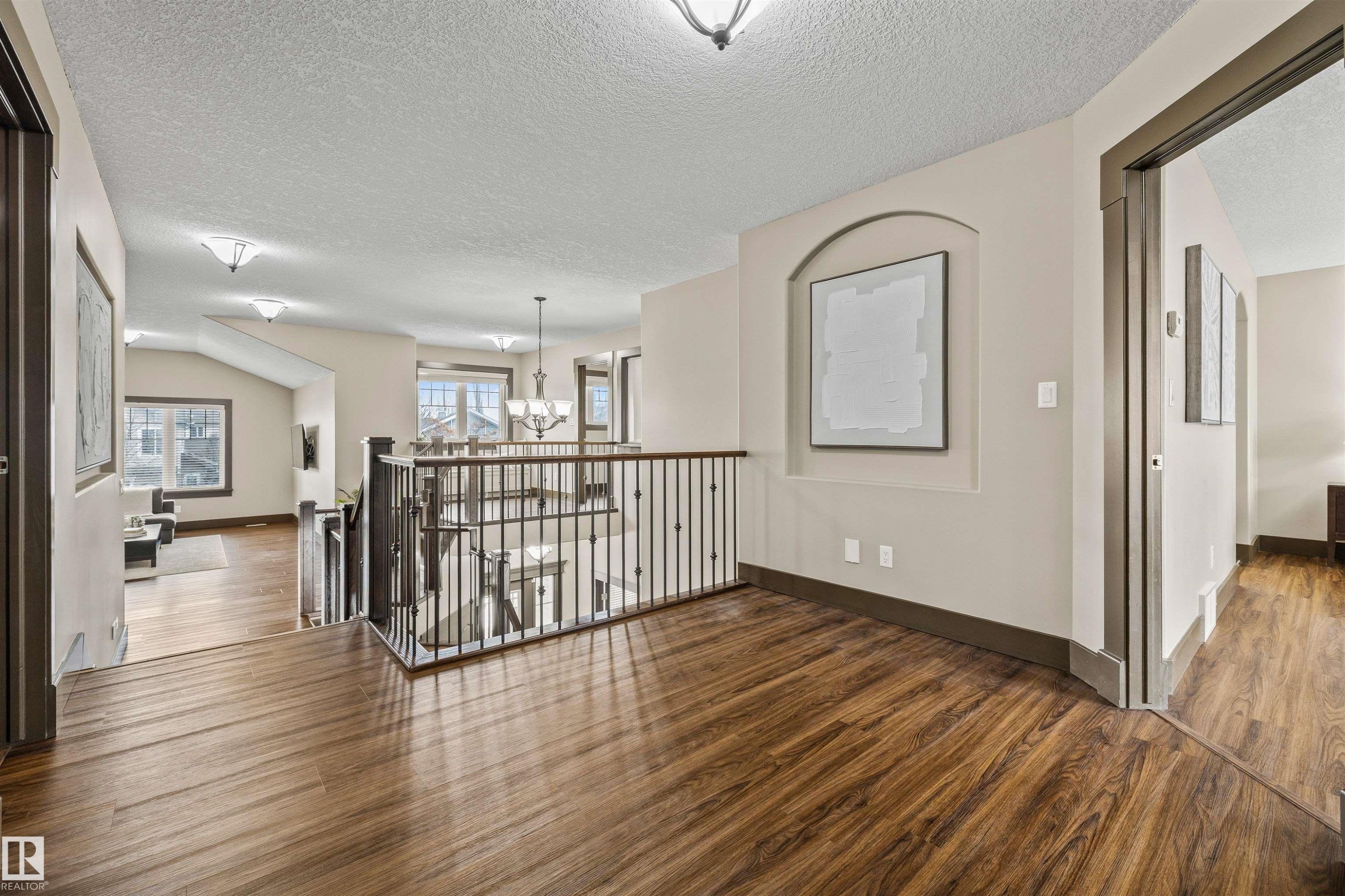 The property features rich wood flooring throughout, a decorative wall niche, and an open railing overlooking the space below - 1014 Hope Road, Edmonton, AB - Indoor Photo Showing Other Room